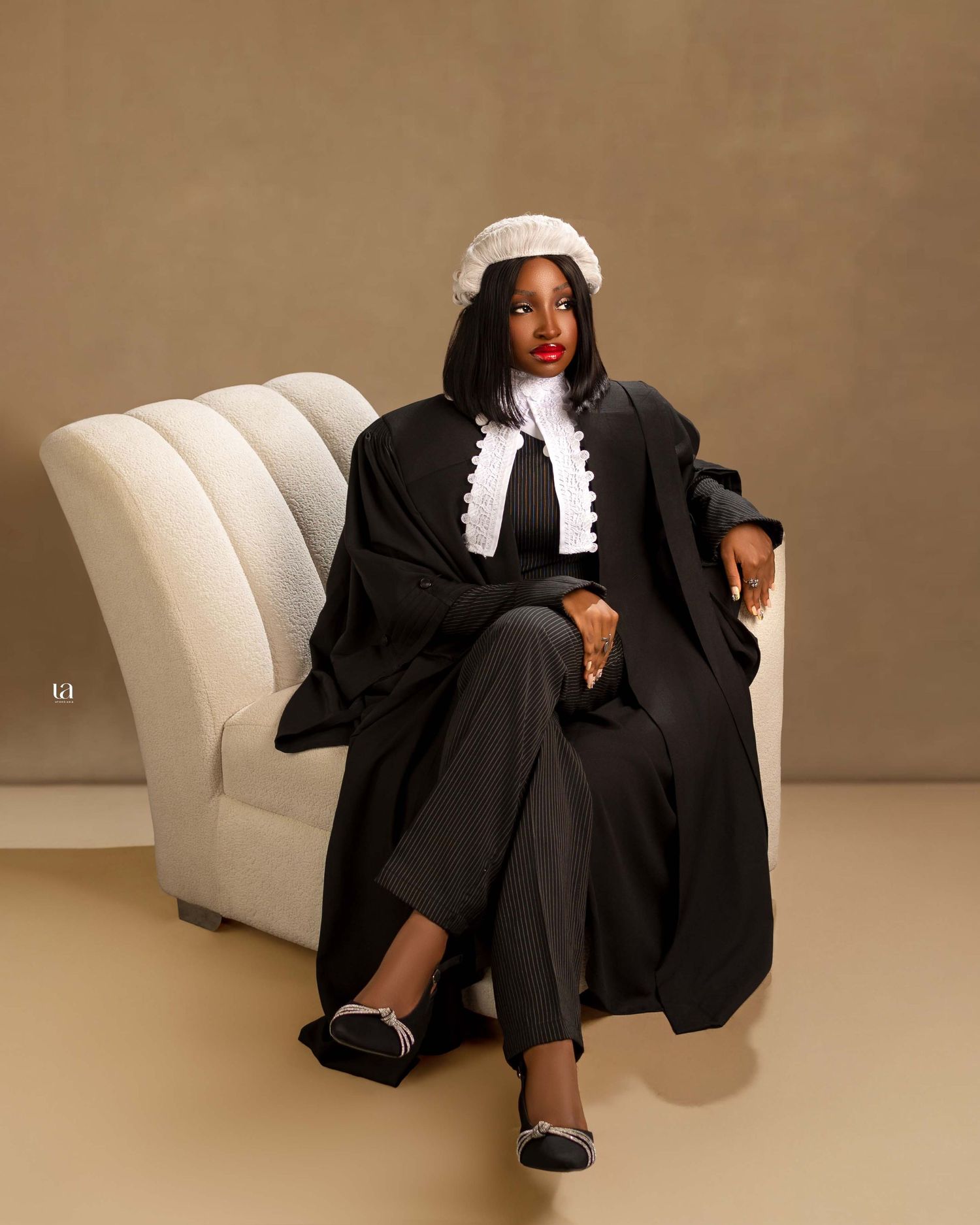 Artistic portrait series in a black and white formal outfit lounging on a modern white sofa.
