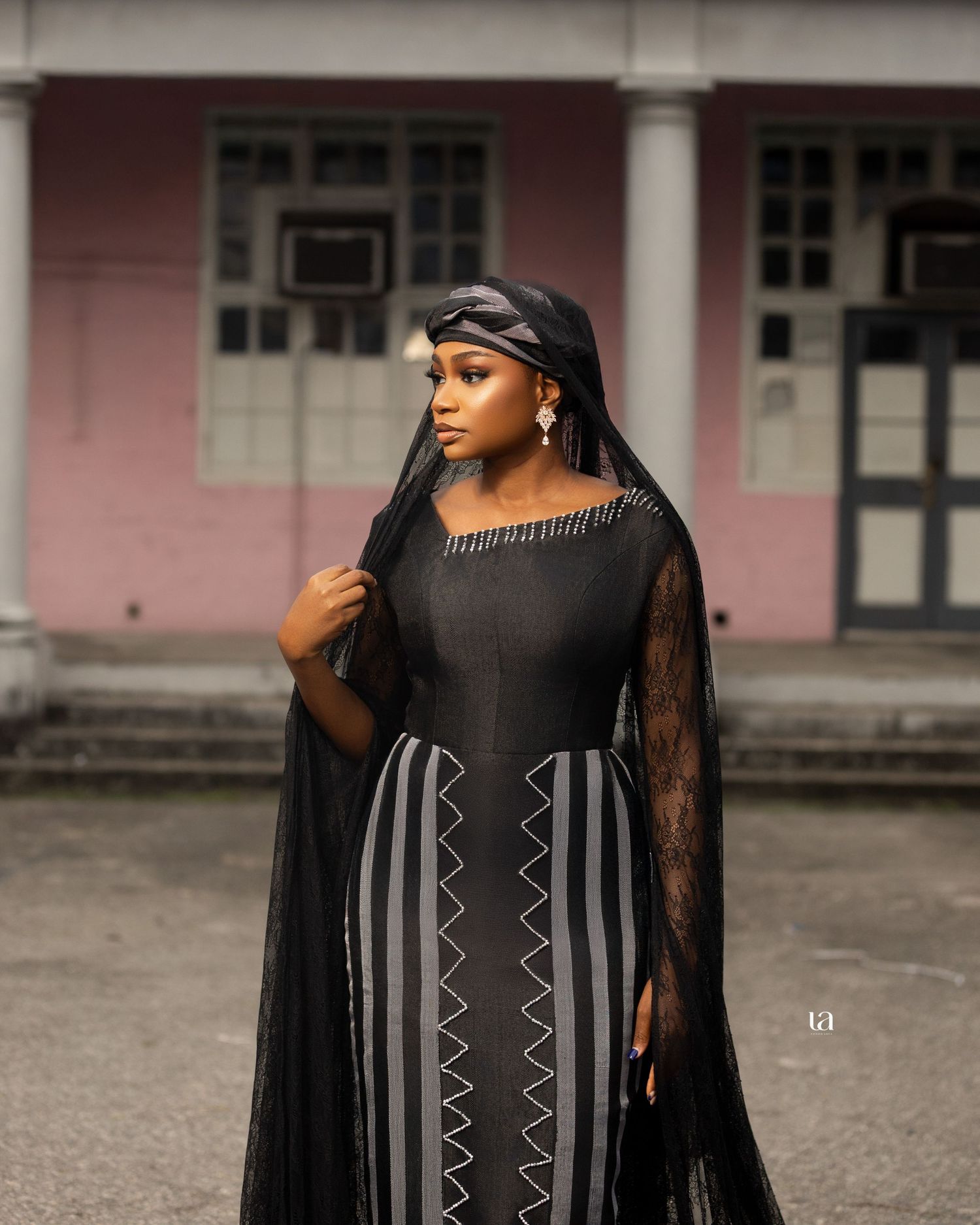 Elegant black dress with geometric patterns photographed against classic colonial architecture.