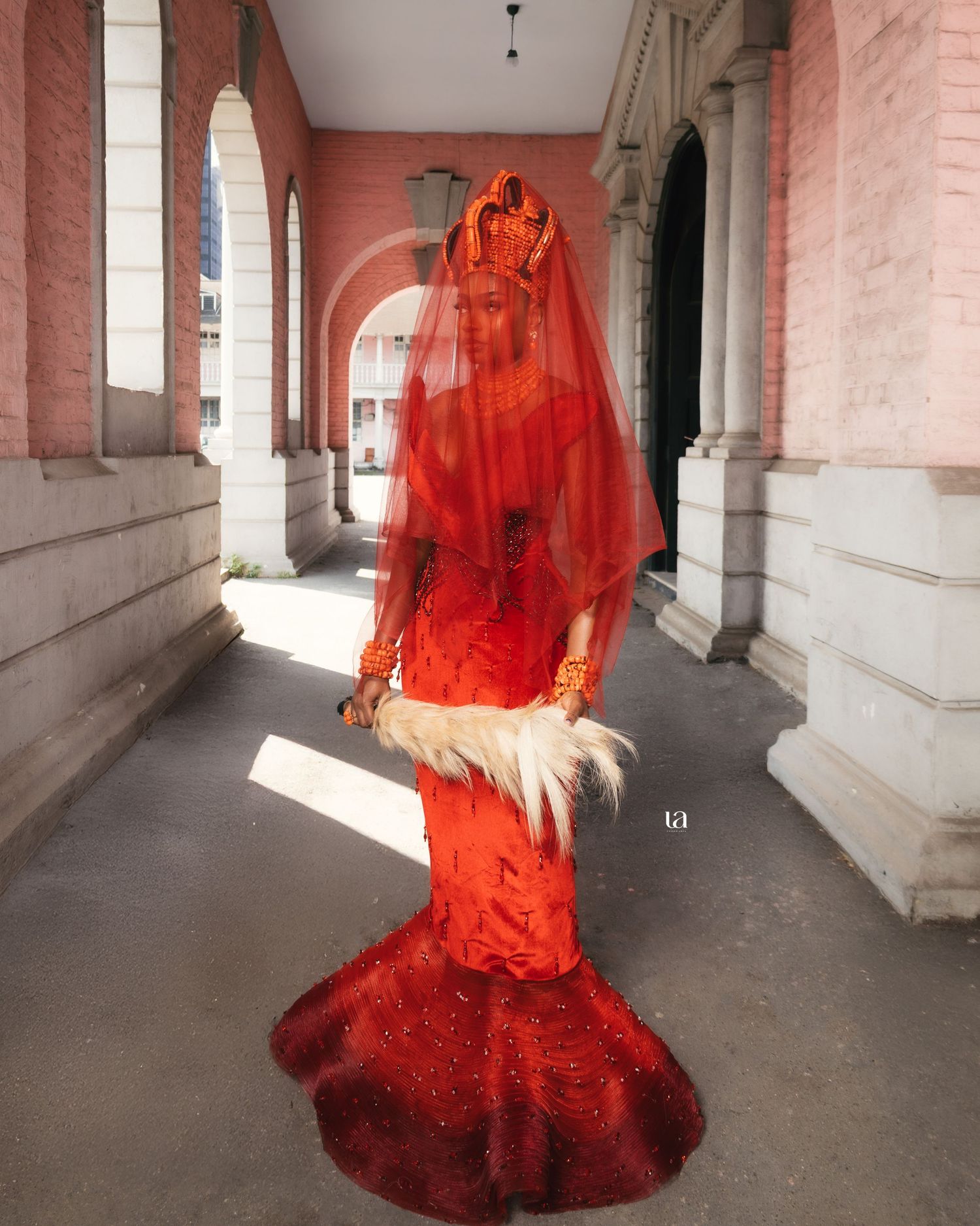 Flowing red dress creates dramatic movement in colonial architecture hallway.
