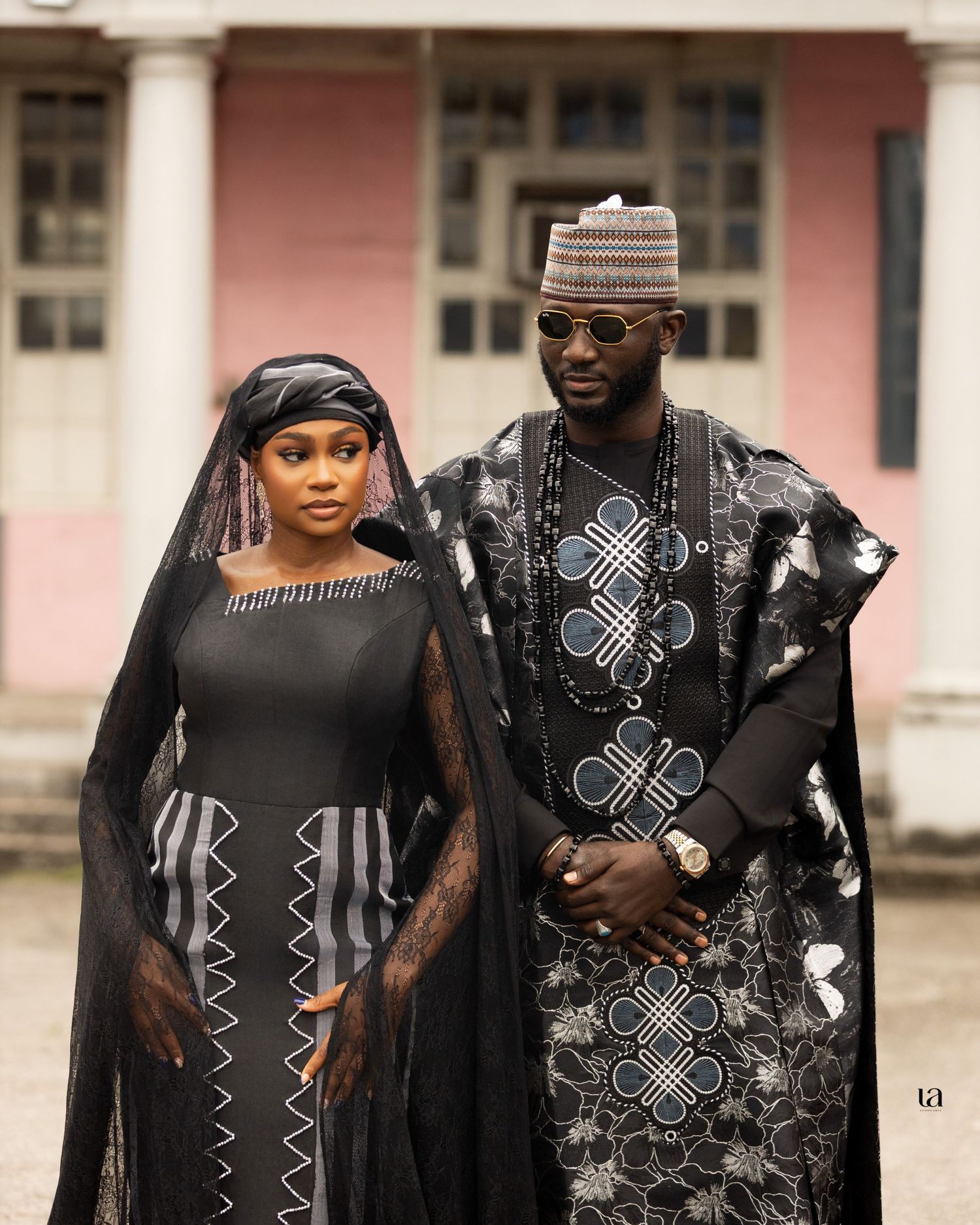 Couple wearing matching black traditional African outfits with intricate embroidery details.