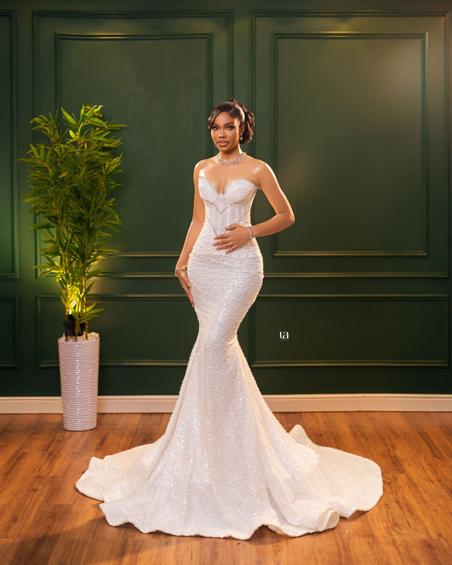 Elegant mermaid style wedding gown with sweetheart neckline displayed on hardwood floor.