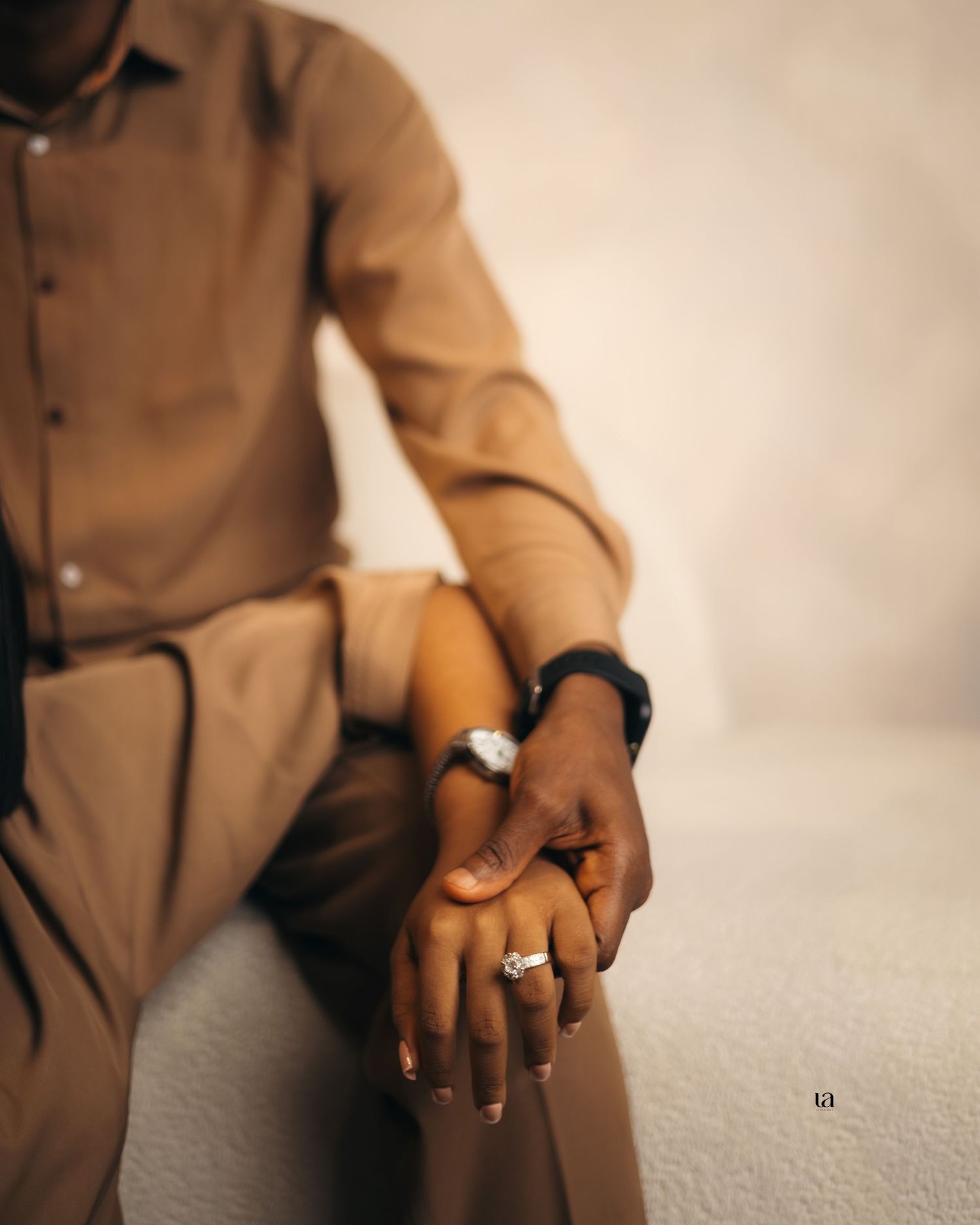Close-up details of hands and tan suit during intimate couples photoshoot.