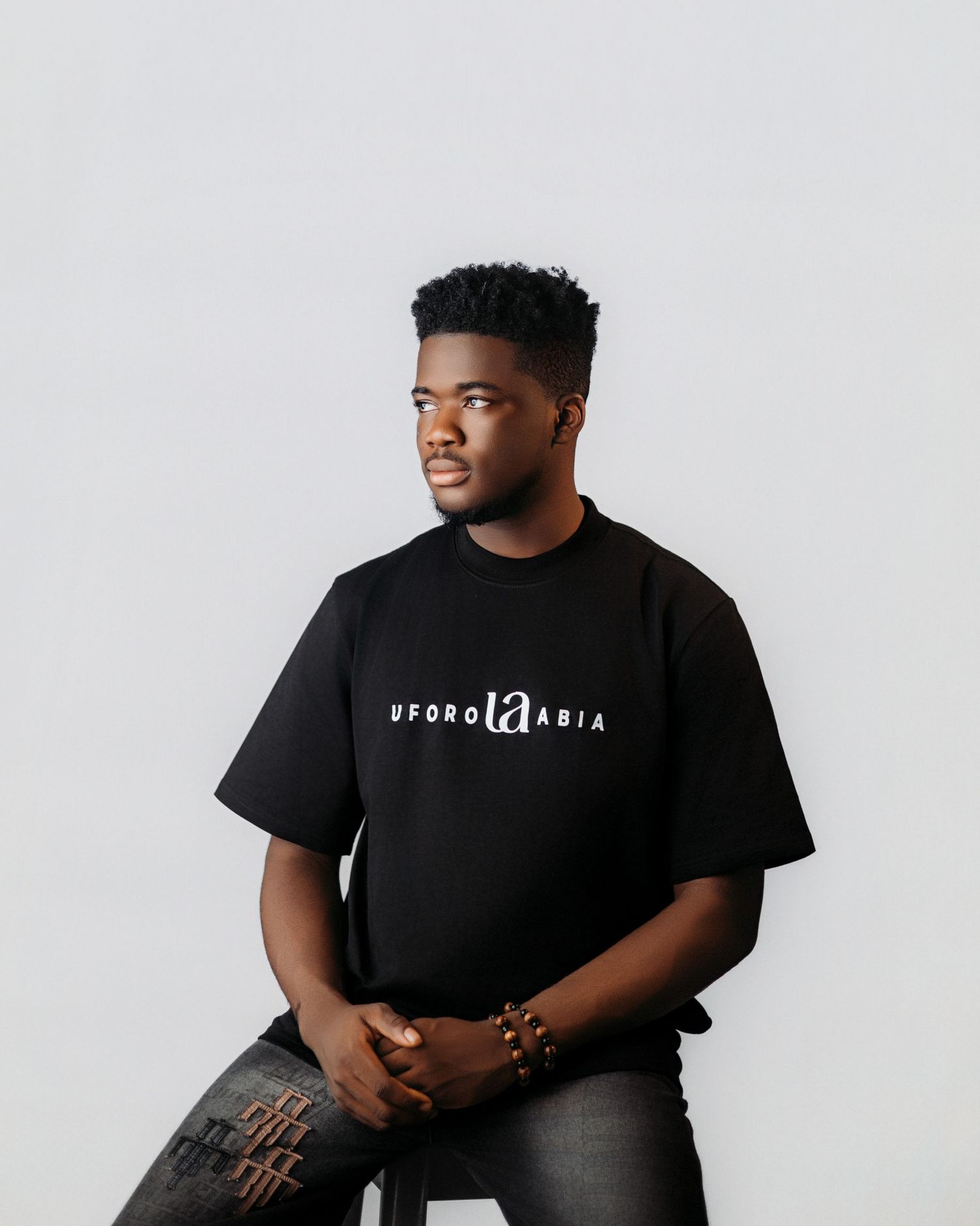 Portrait of person in black branded t-shirt against white background.