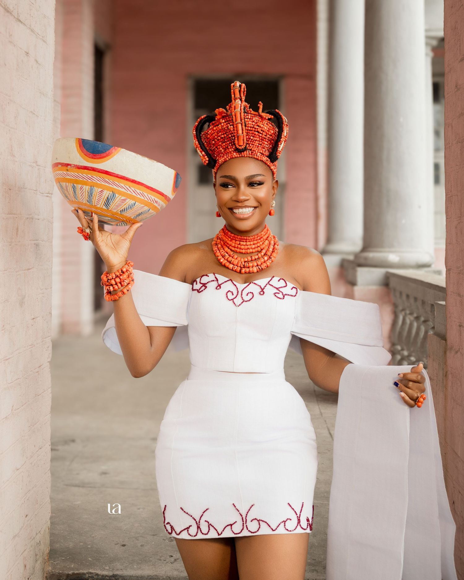 Wedding fashion photoshoot featuring white dresses with orange accents against colonial columns.