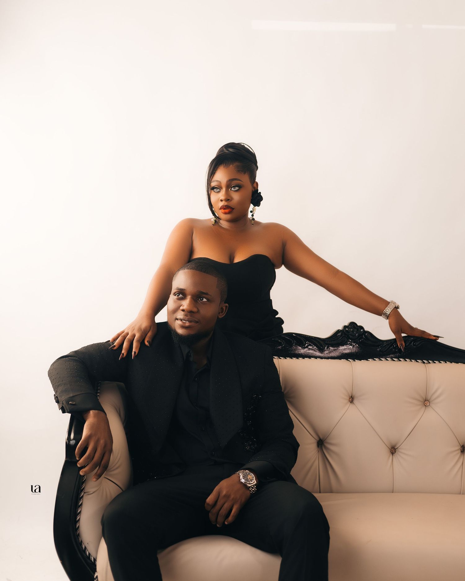 Intimate couple's portrait session on beige couch showing affectionate poses in black attire.