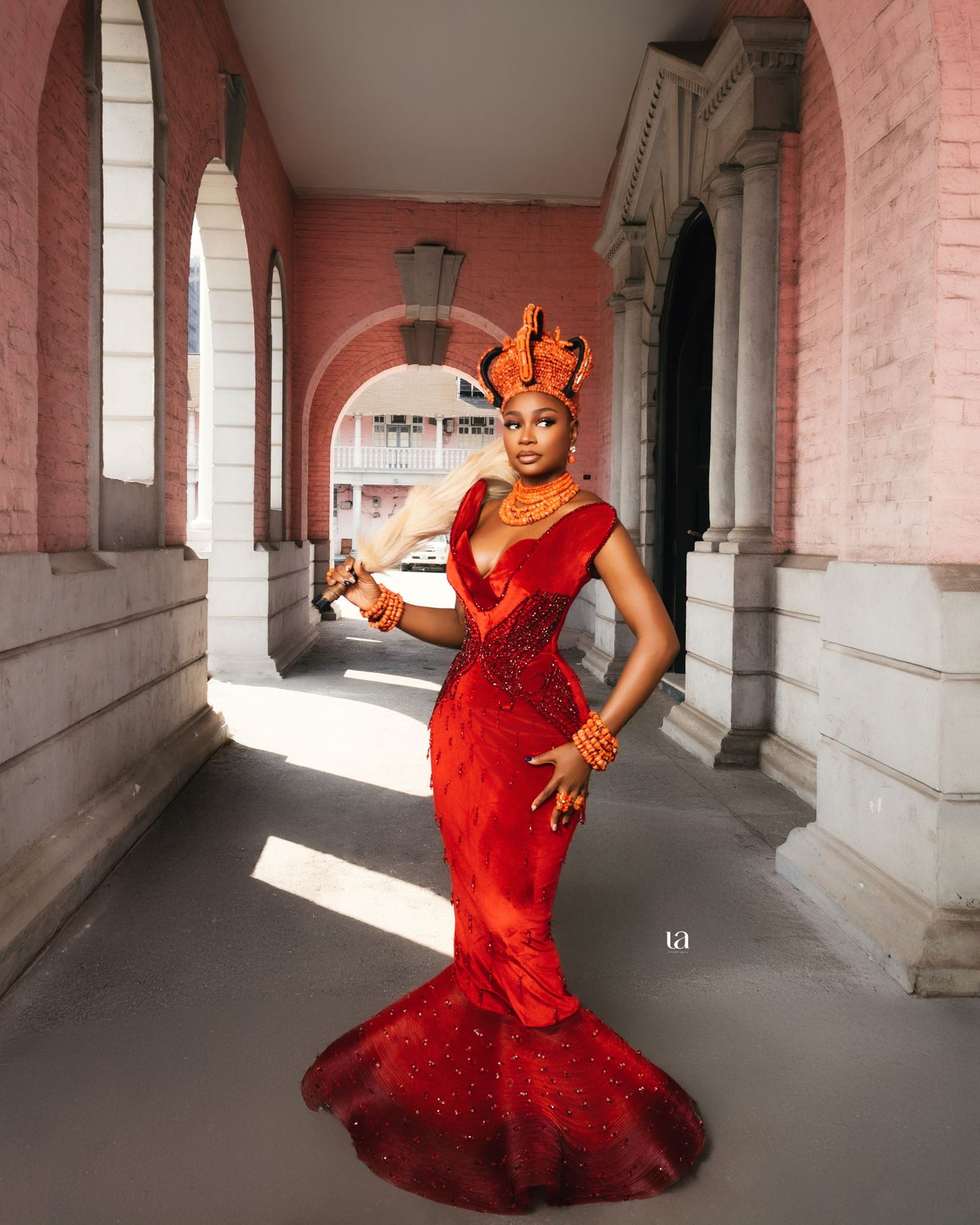 Dynamic photo series of red formal dress with dramatic poses in architectural setting.
