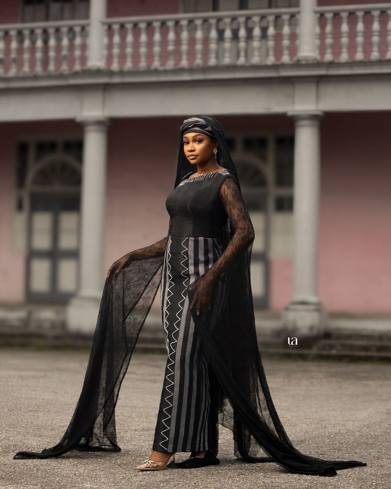 Dramatic portrait series in black lace outfit against historic pink building backdrop.