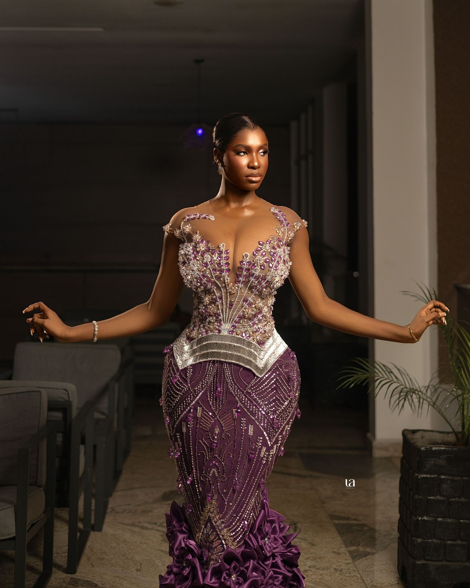 Dramatic purple evening gown with beaded bodice and ruffled skirt showcased in indoor setting.