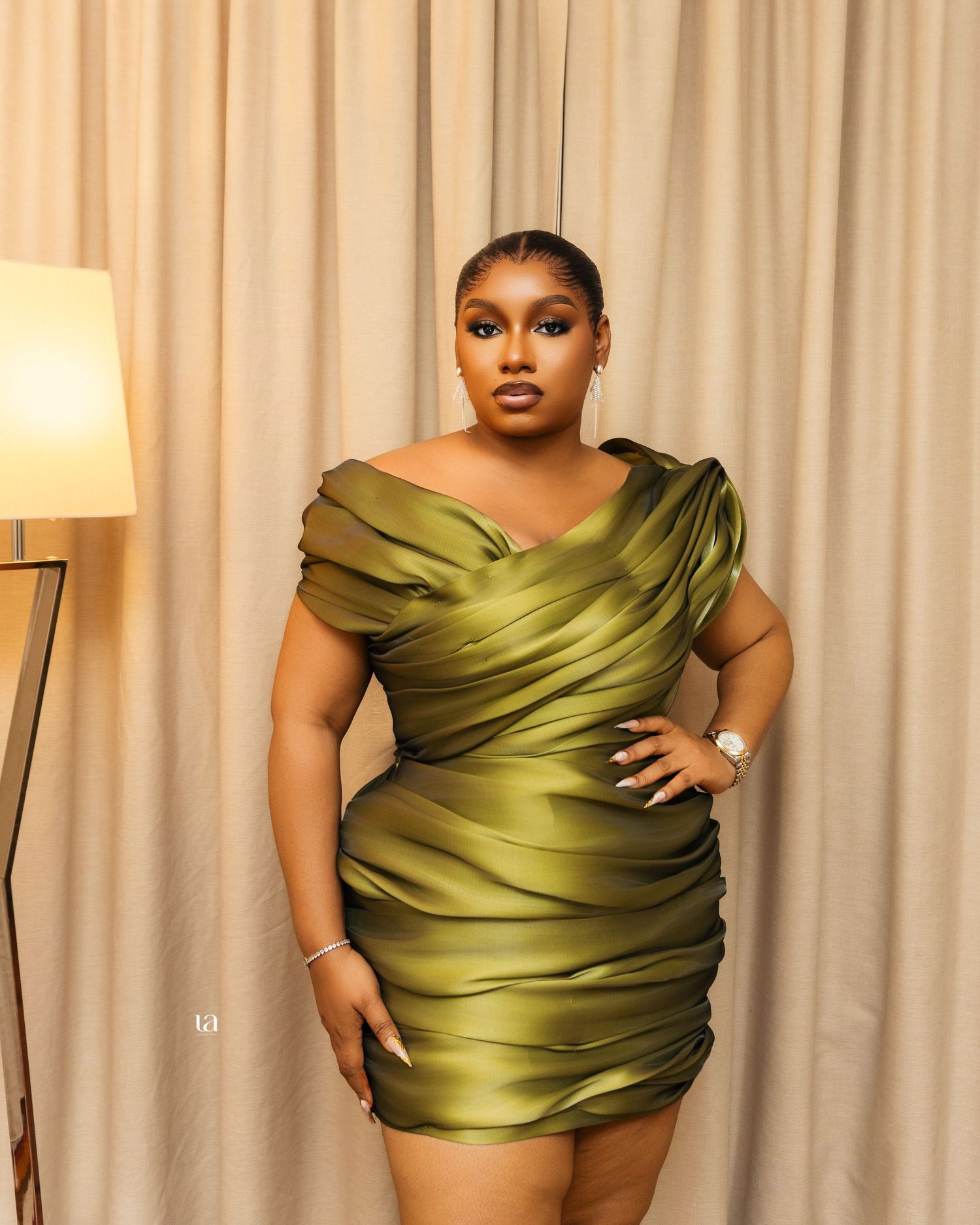 Professional fashion photoshoot featuring an elegant olive green satin wrap top against a neutral backdrop.