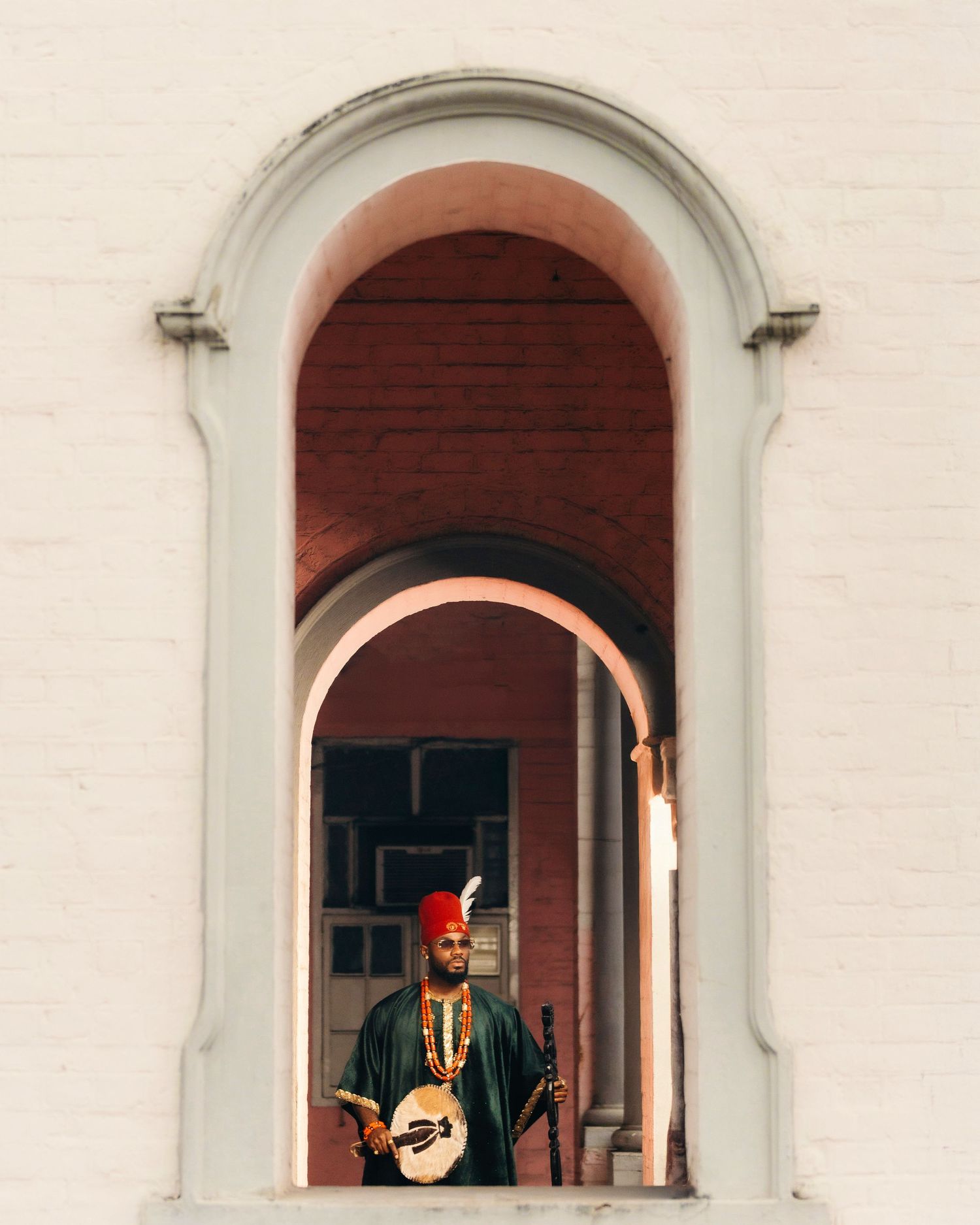 Person in ceremonial dress photographed through multiple white arched windows.