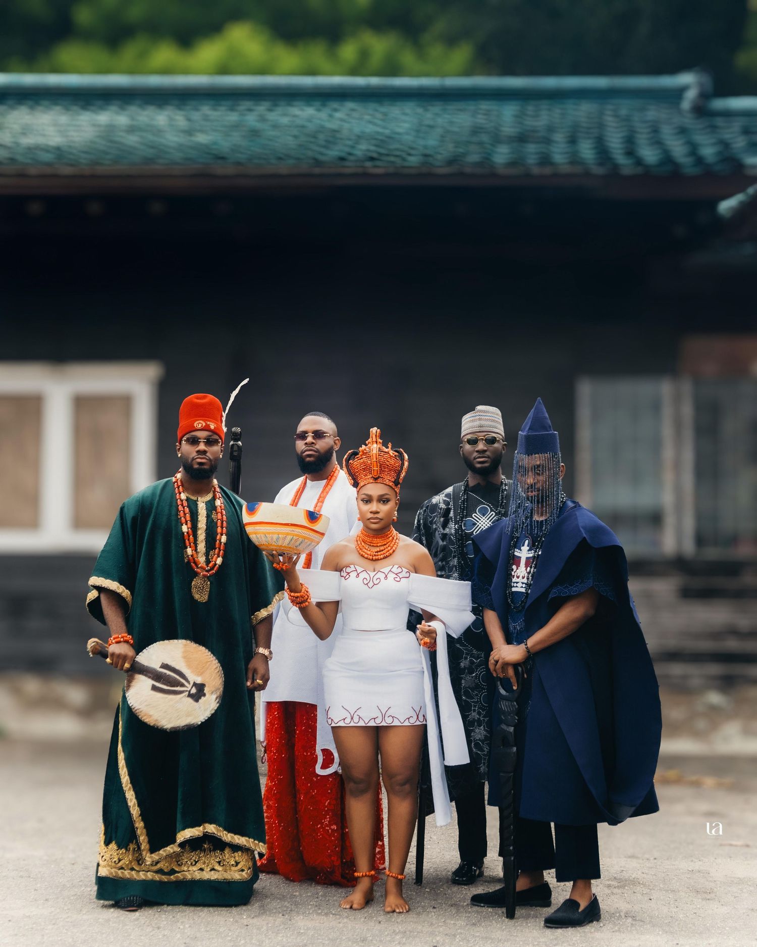 Traditional cultural celebration with people in traditional attire holding ceremonial objects outdoors.