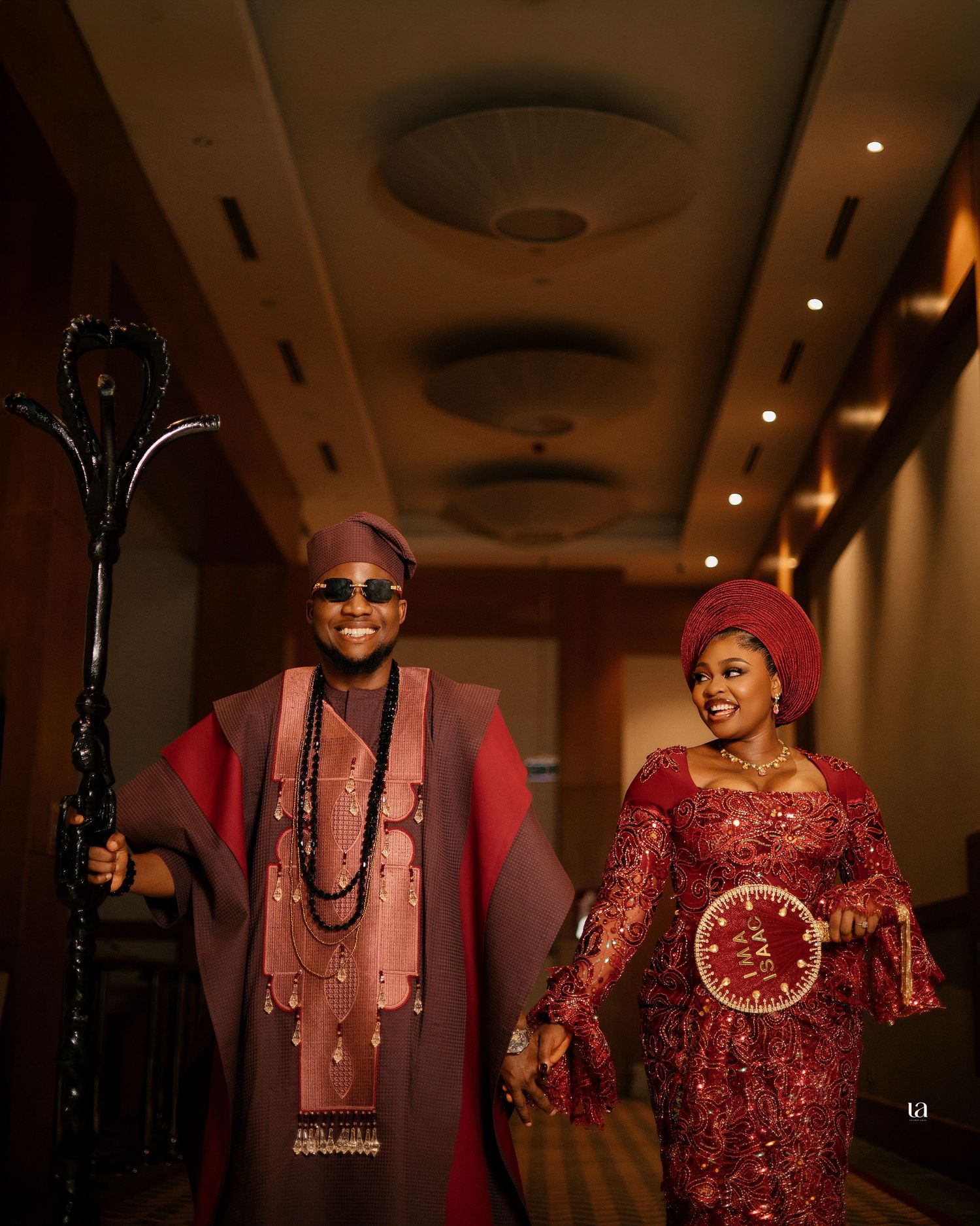 Indoor event photography featuring traditional African formal wear in rich red tones.