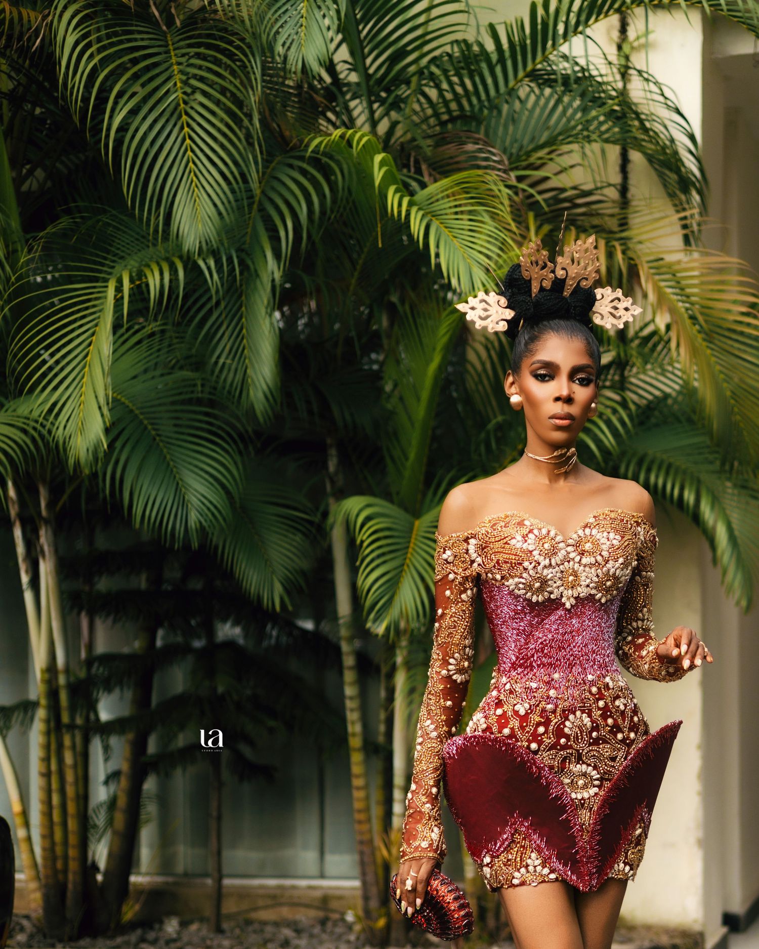 Fashion shoot among tropical palm trees featuring burgundy and gold formal wear.