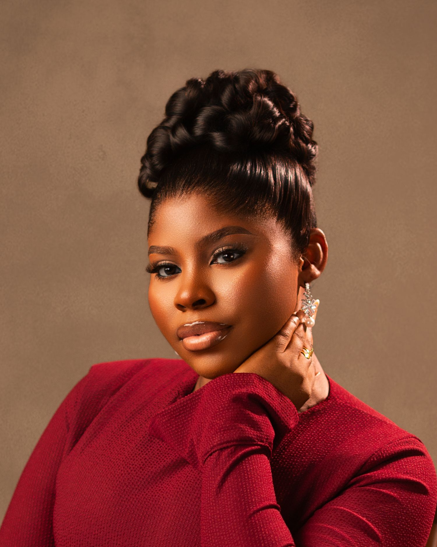 A portrait in warm tones featuring elegant styling with a red sweater and statement earrings.
