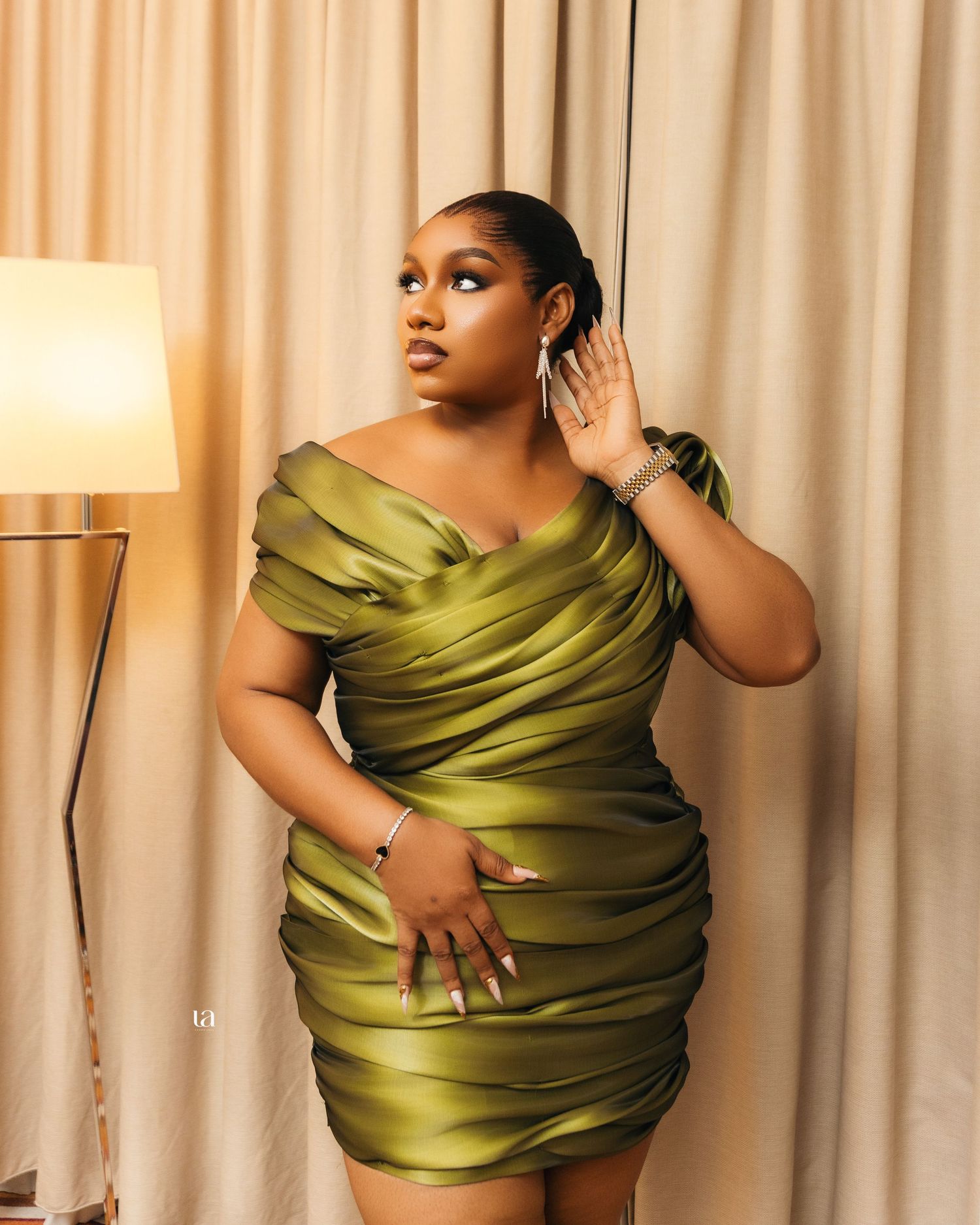 Artistic poses in olive green satin wrap against cream curtain backdrop.
