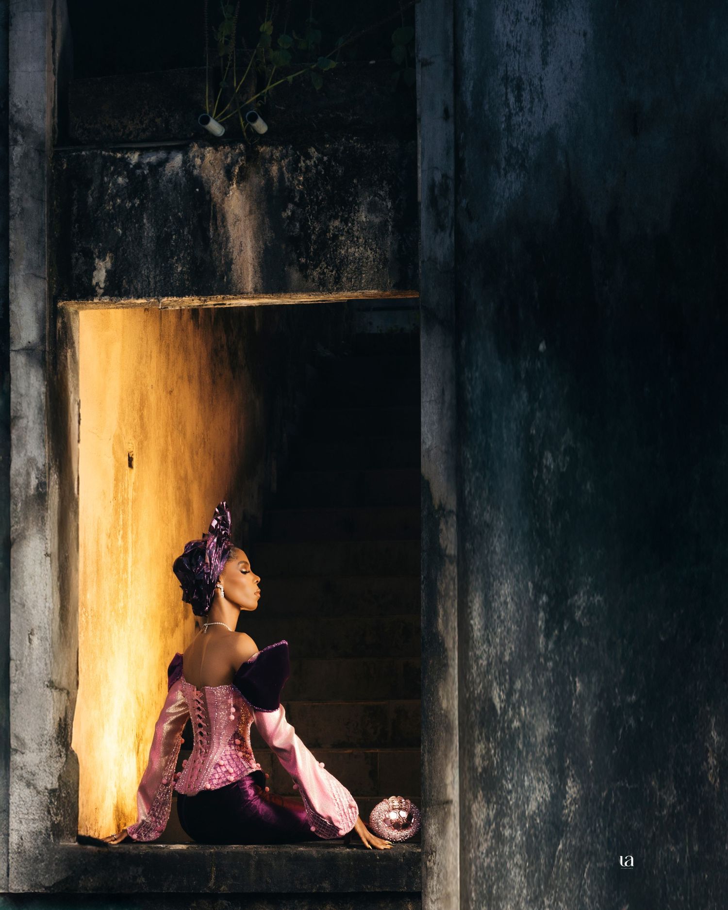 Dramatic fashion portrait in dark setting with light streaming through windows.