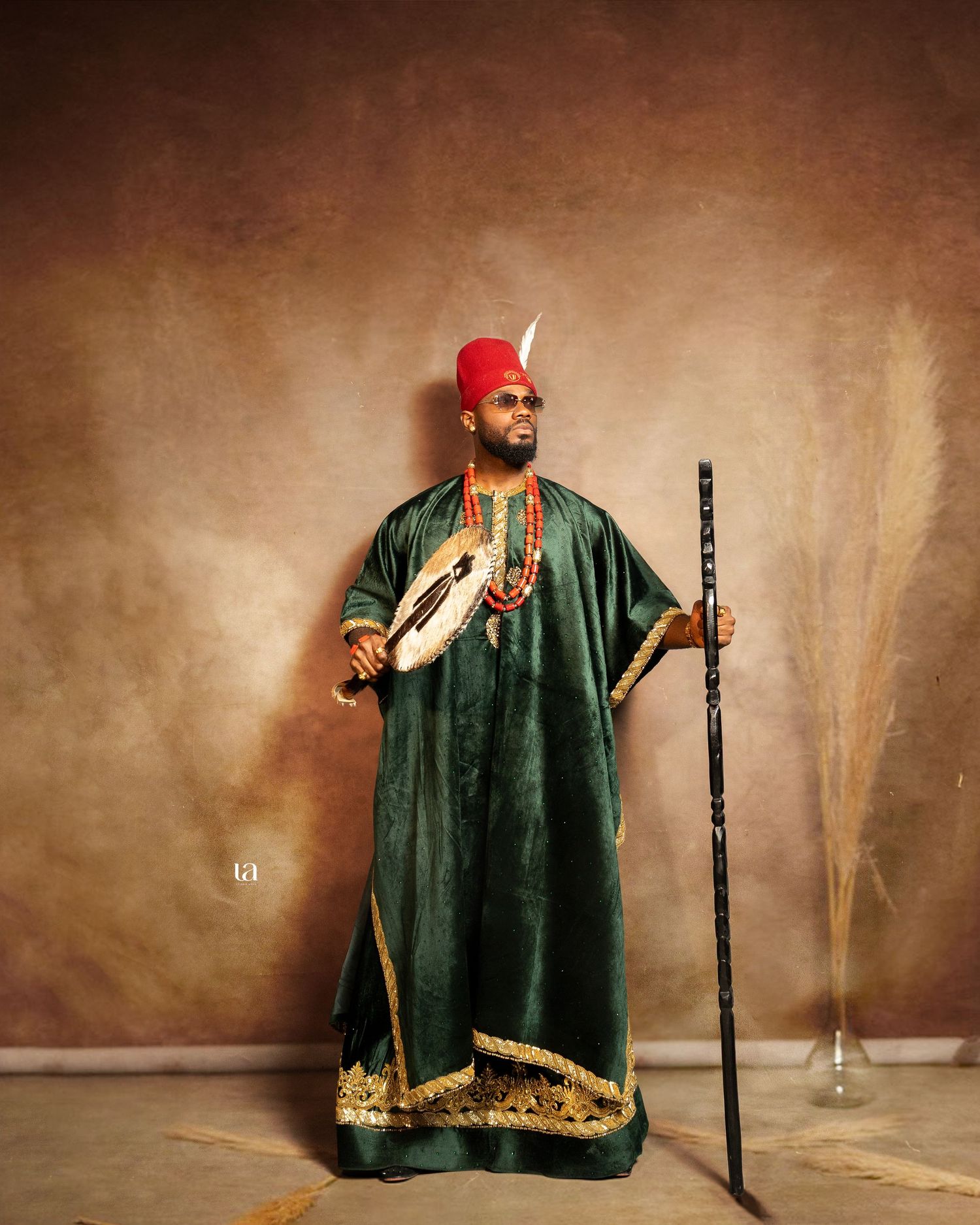 Traditional ceremonial performance in emerald green robe with gold trim against sepia background.