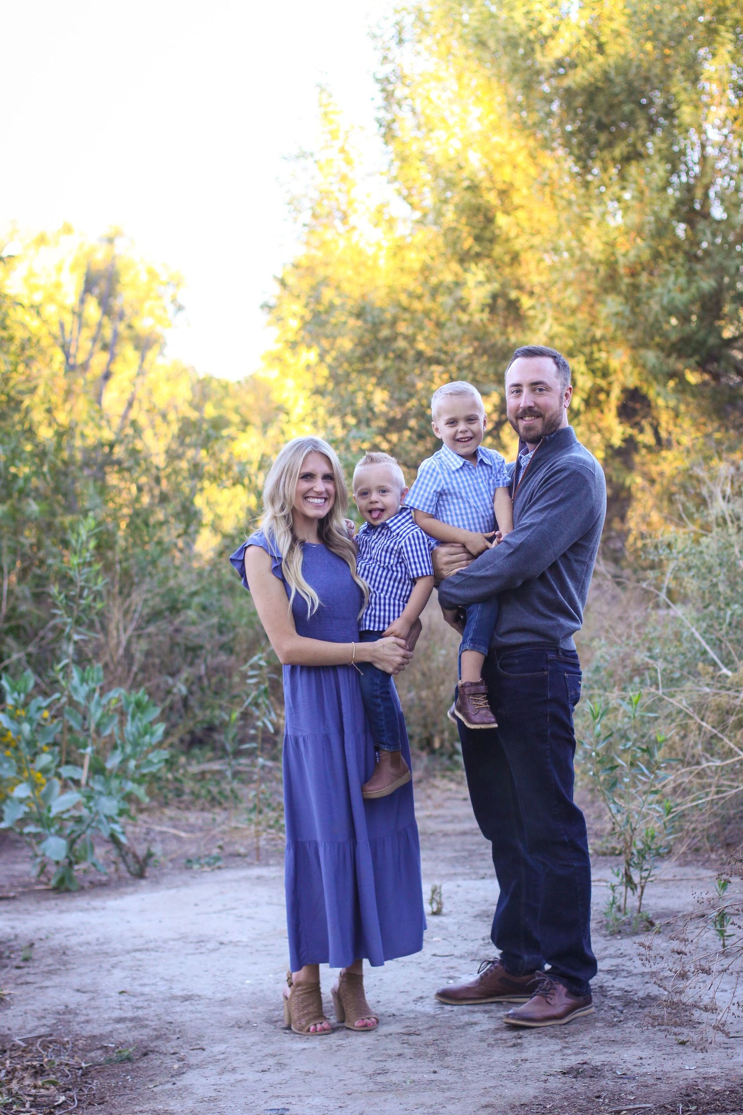 Family members in coordinated blue outfits interact during golden hour photo session.
