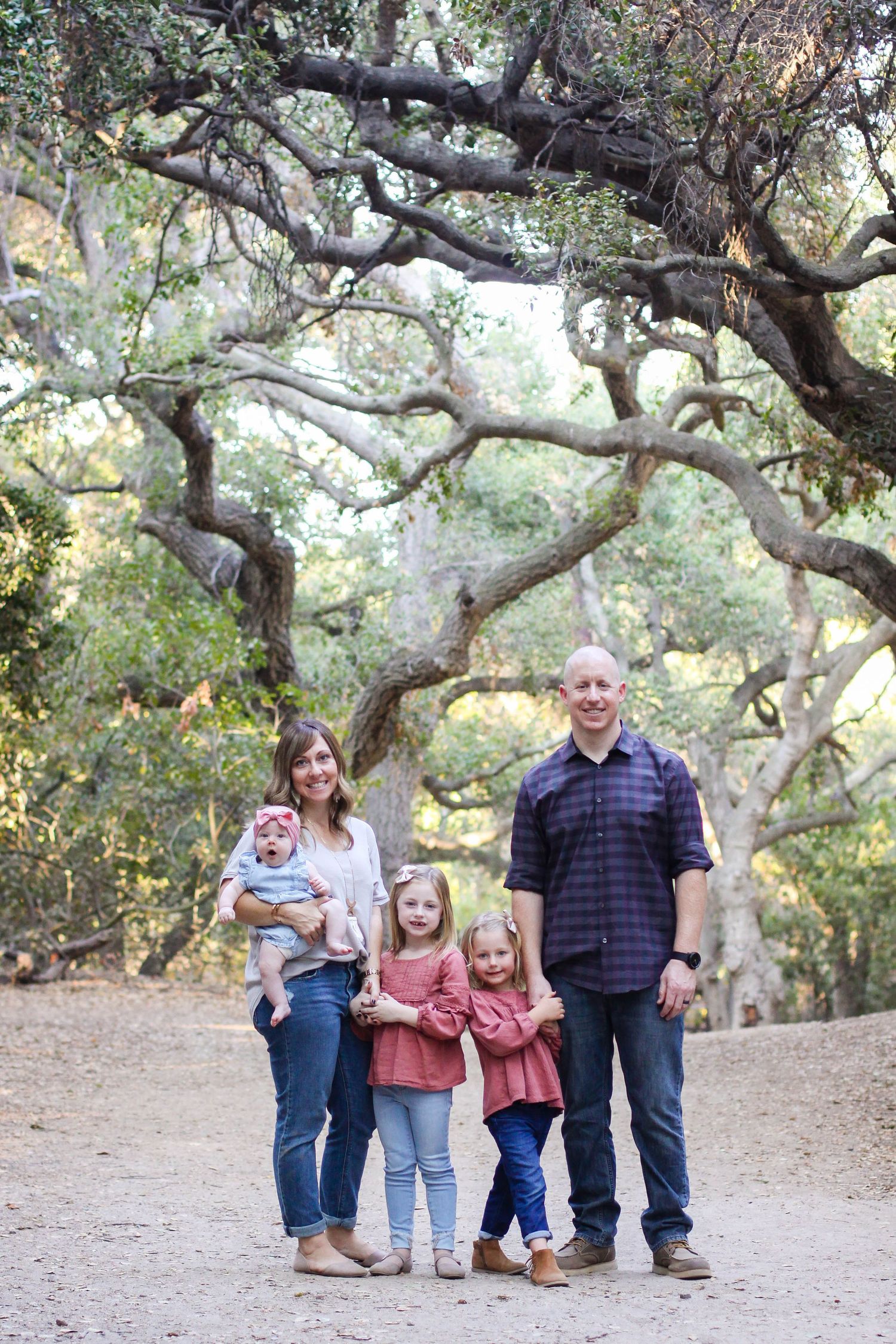 Family group poses under majestic oak trees in a natural setting.