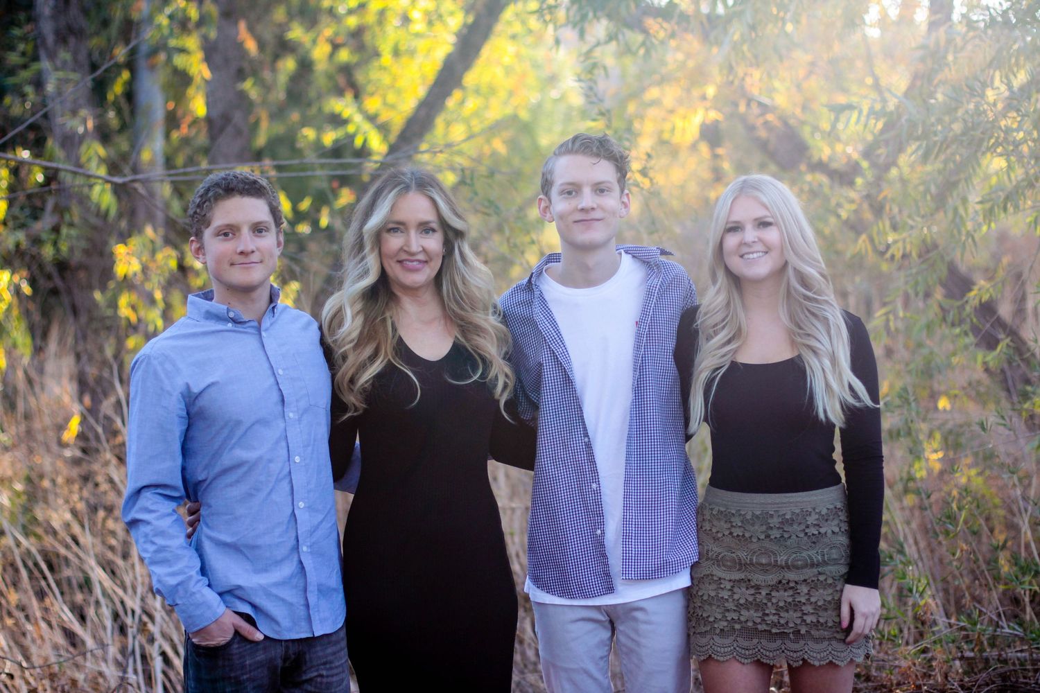 Family photo session in casual attire during golden hour with trees in background.