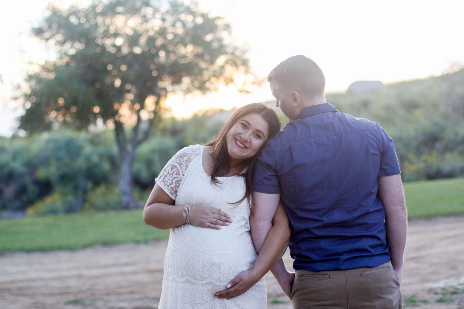 Romantic couple embraces while walking along a scenic outdoor path during golden hour sunset.