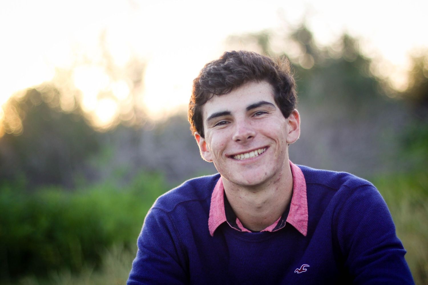 Outdoor portrait session in natural lighting with blue shirt against blurred background.