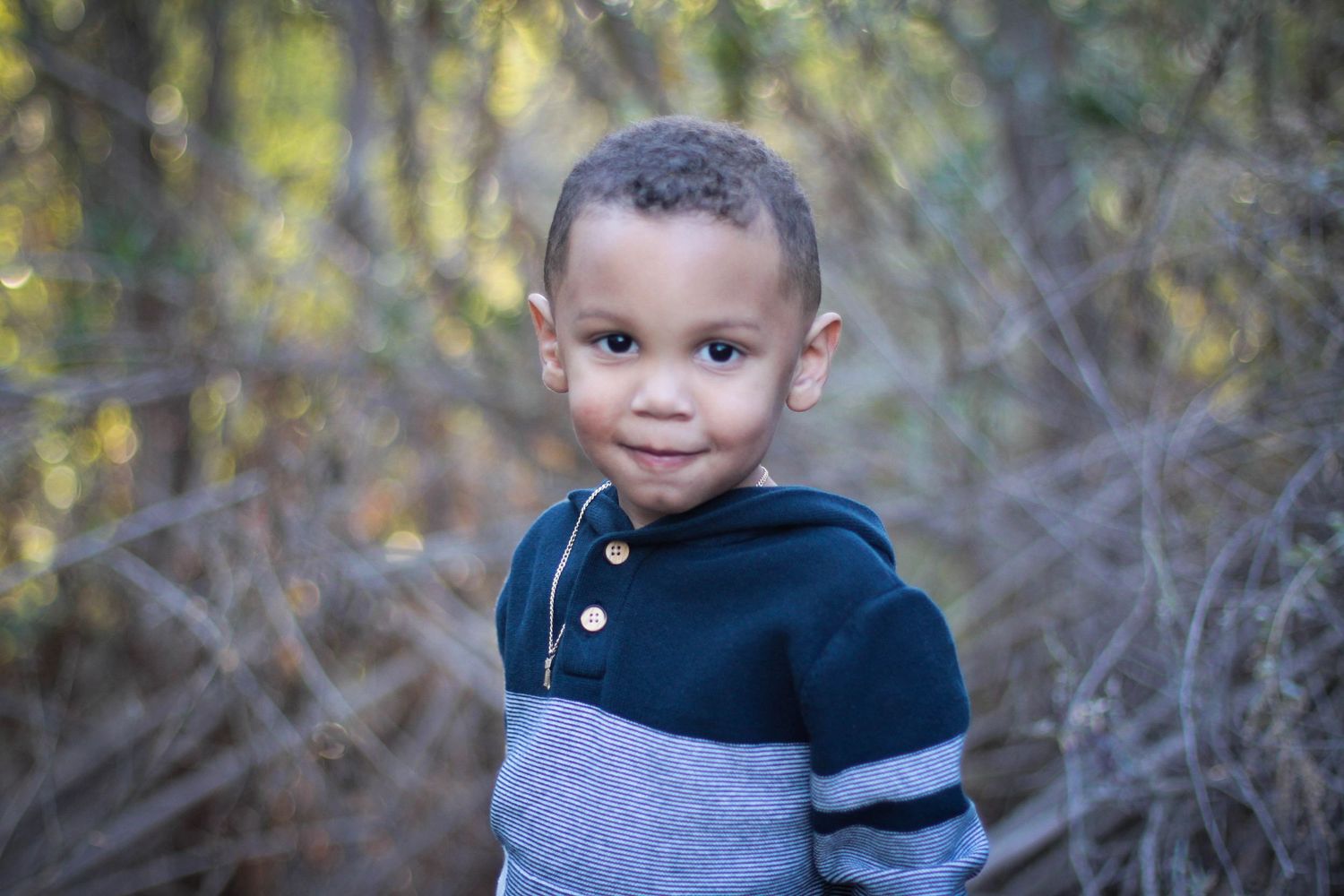 Young child in striped sweater during outdoor portrait session.