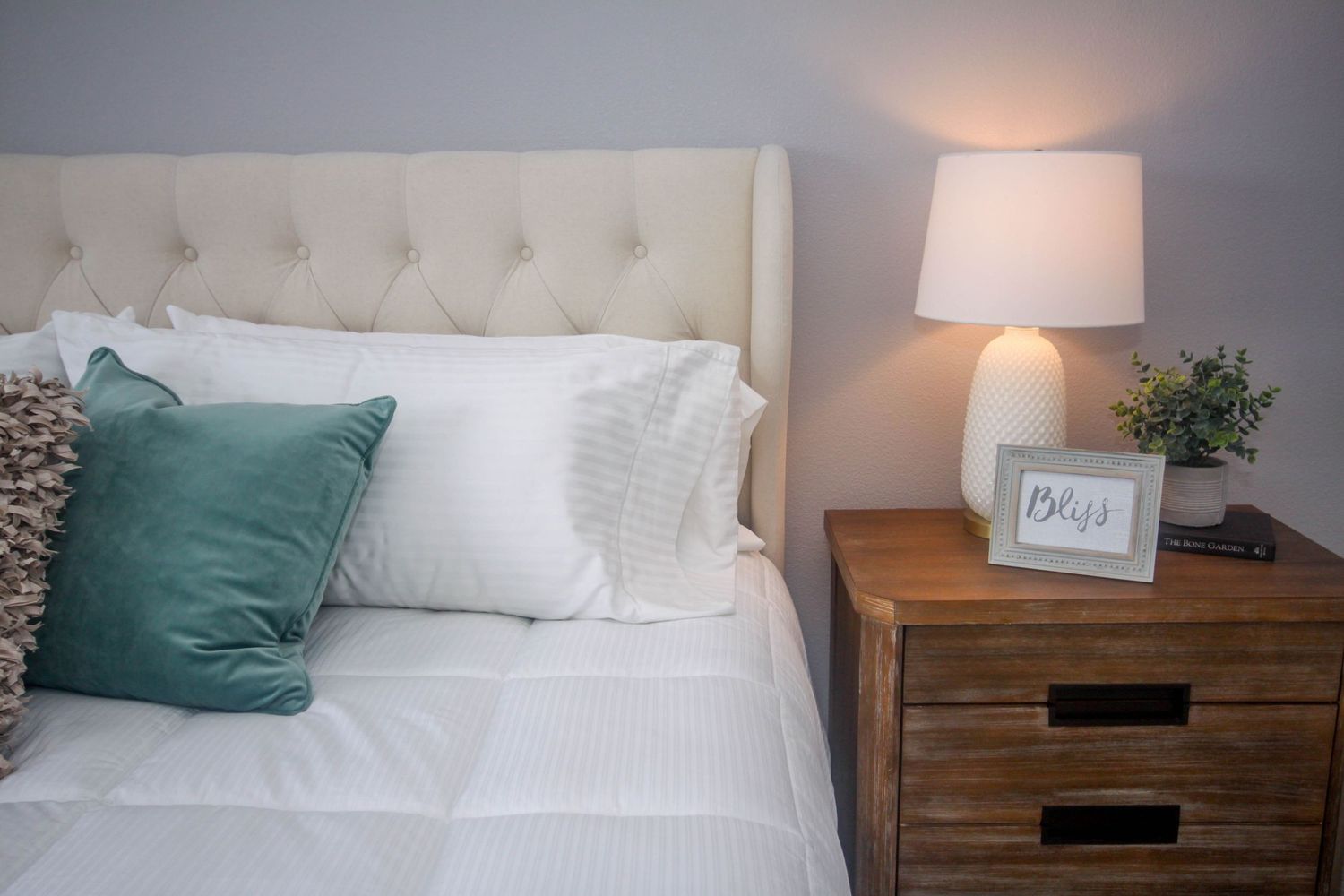 Modern bedroom interior with tufted headboard and wooden nightstands.