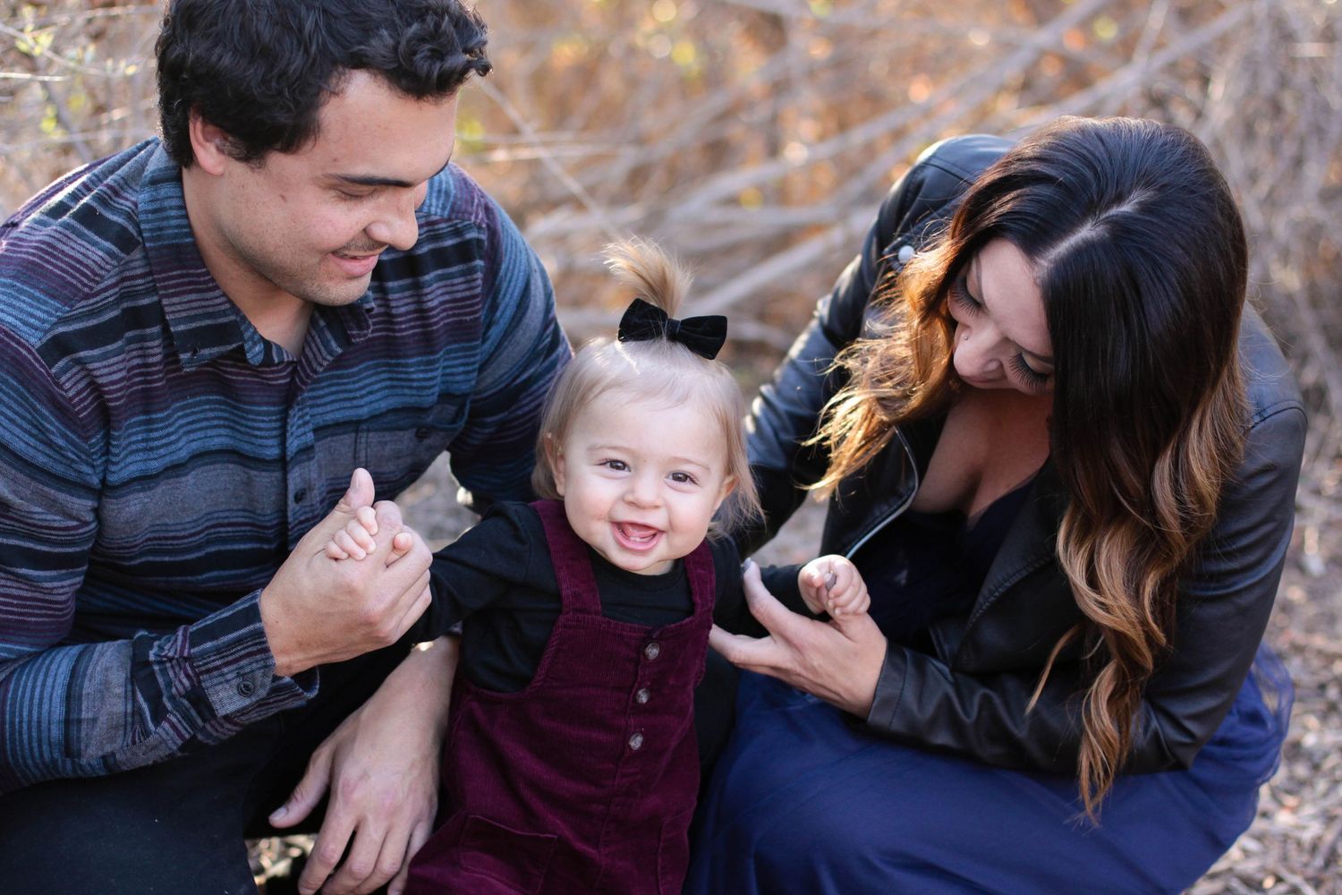 Family portrait session outdoors with casual clothing and natural expressions.