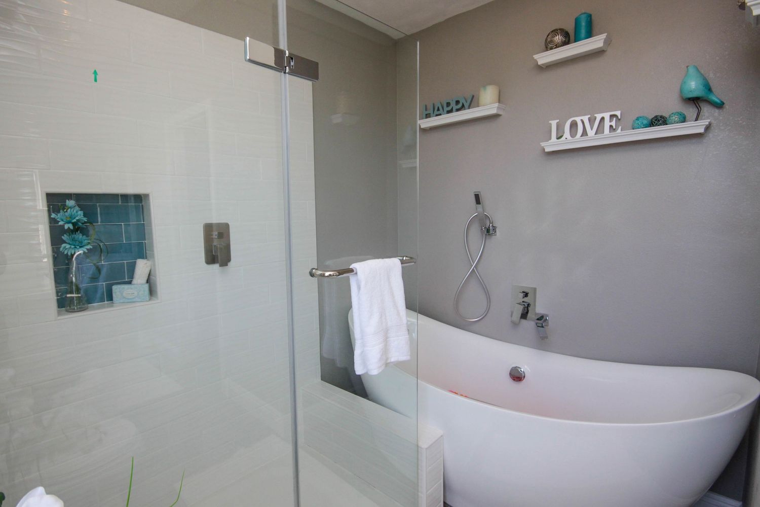 Luxurious bathroom featuring a freestanding tub, glass shower enclosure, and turquoise decor accents.