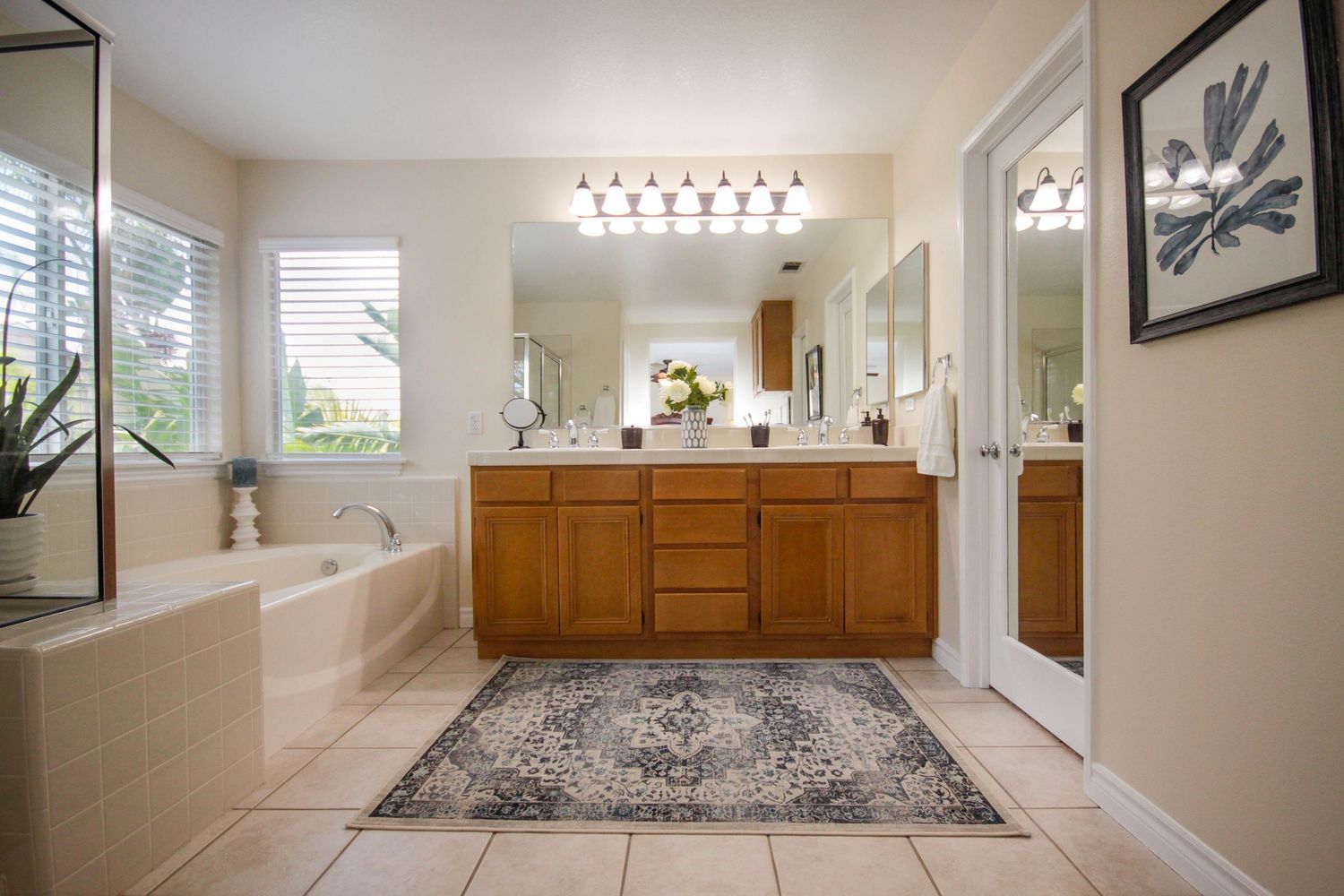 Modern master bathroom with white cabinets, pendant lighting, and gray tile flooring.