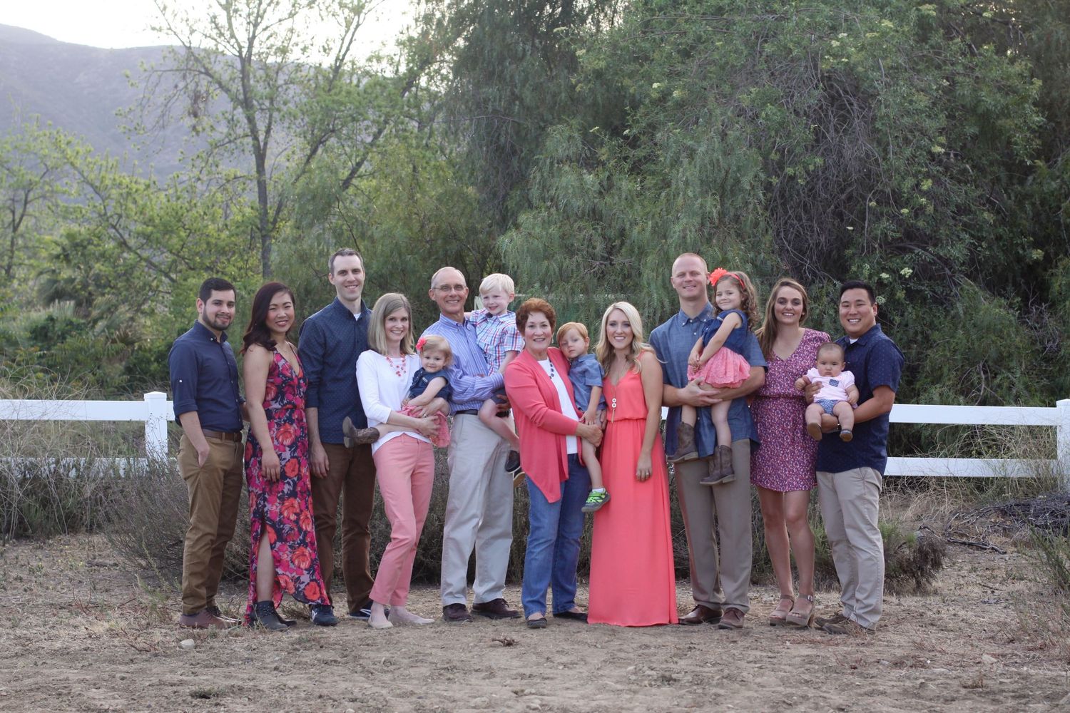 Large family group photo with coordinated outfits against natural backdrop.