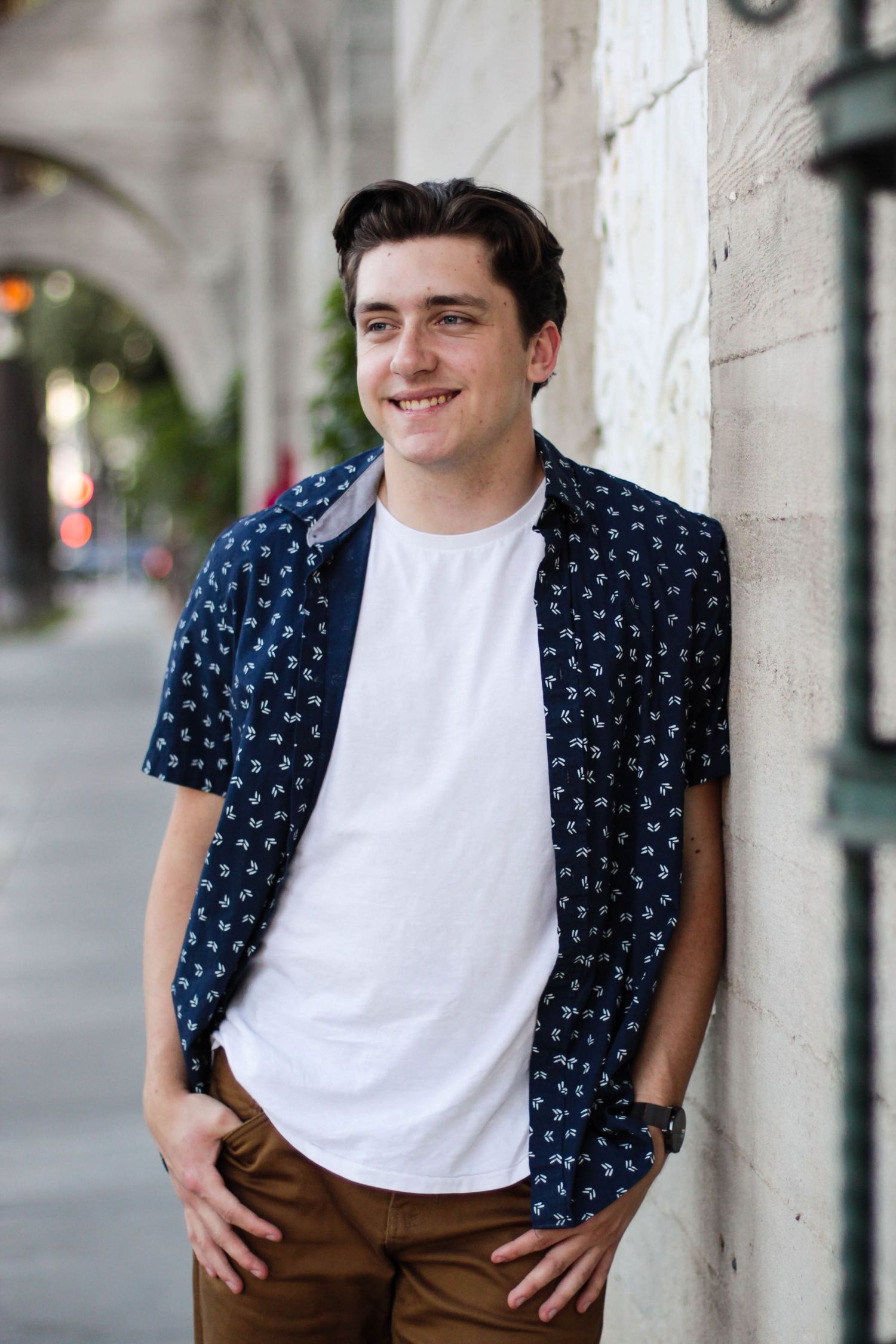 Casual portrait series against white wall wearing navy patterned shirt and white t-shirt.