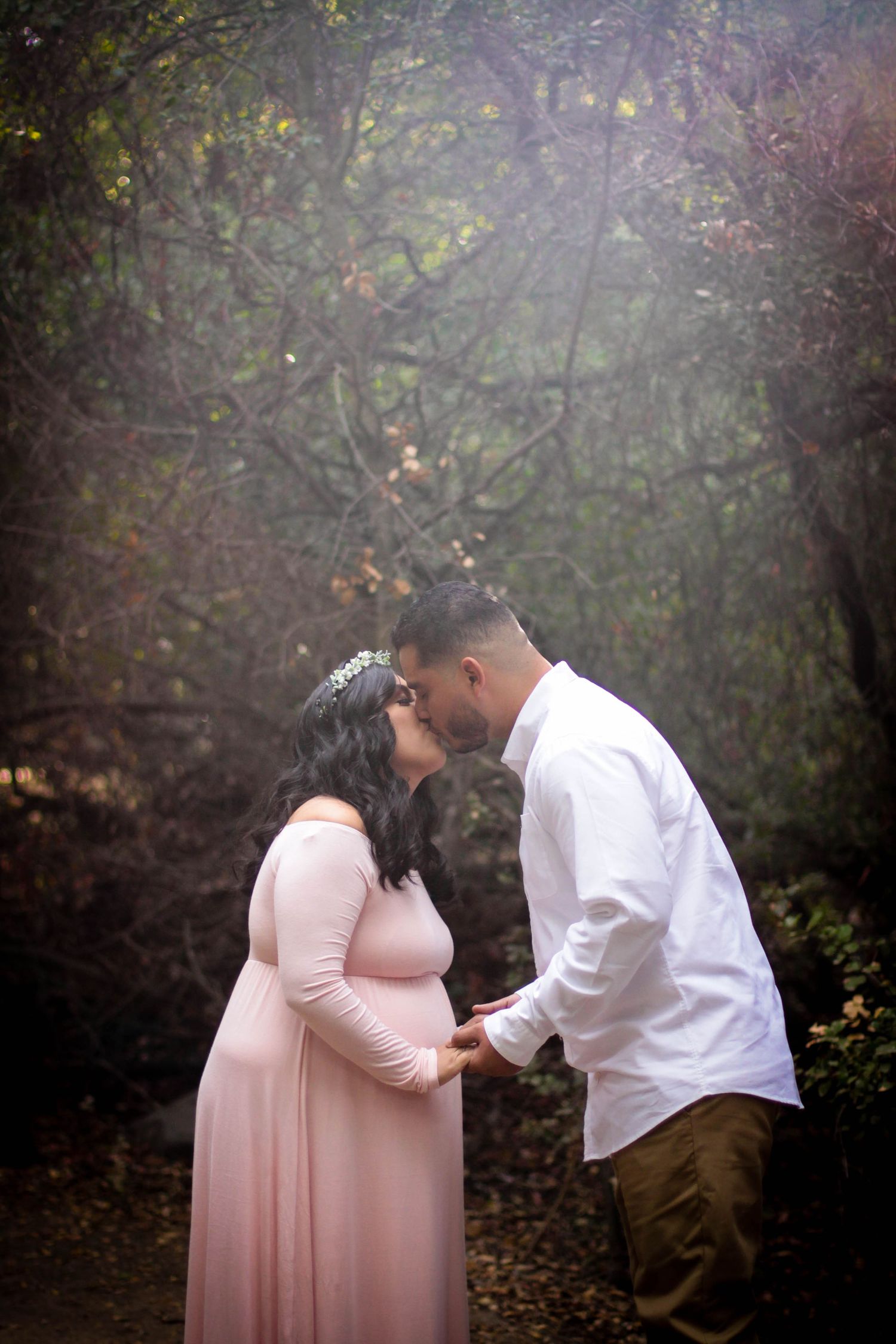 A romantic maternity photoshoot sequence showing tender moments between a couple in a misty forest setting.