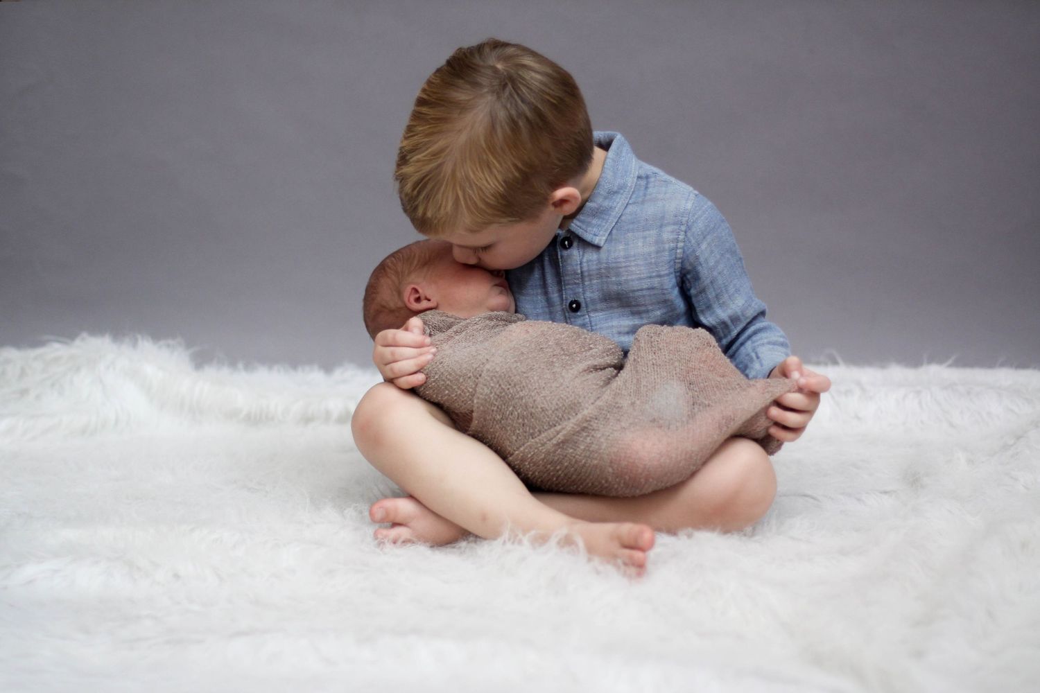 A baby's feet resting on soft white fur while wearing blue denim clothing.