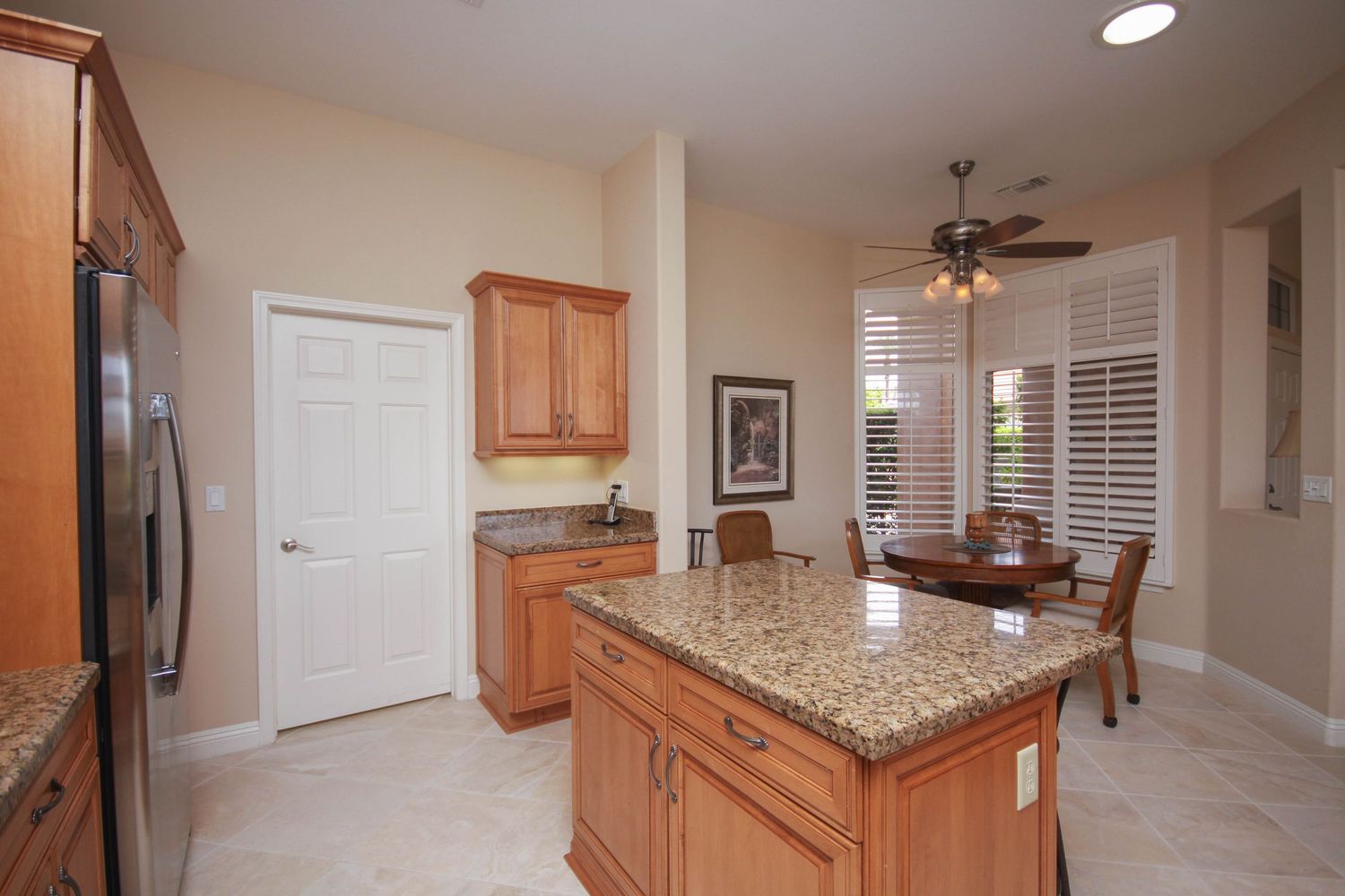 Modern open concept kitchen and dining area with granite countertops and wood cabinets.