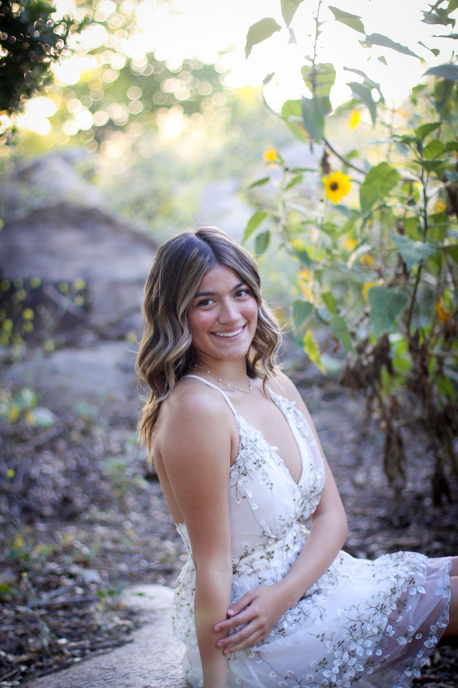 Portrait session in sunflower field wearing white lace dress at sunset.