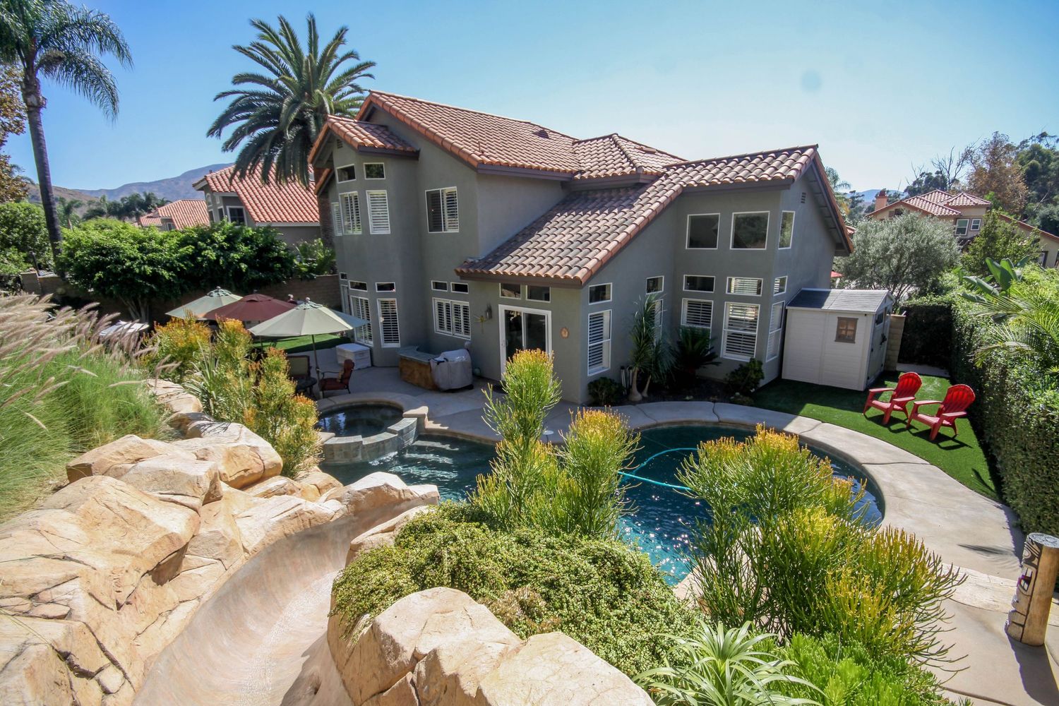 Scenic coastal residential neighborhood with Mediterranean style homes and palm trees along a winding road.