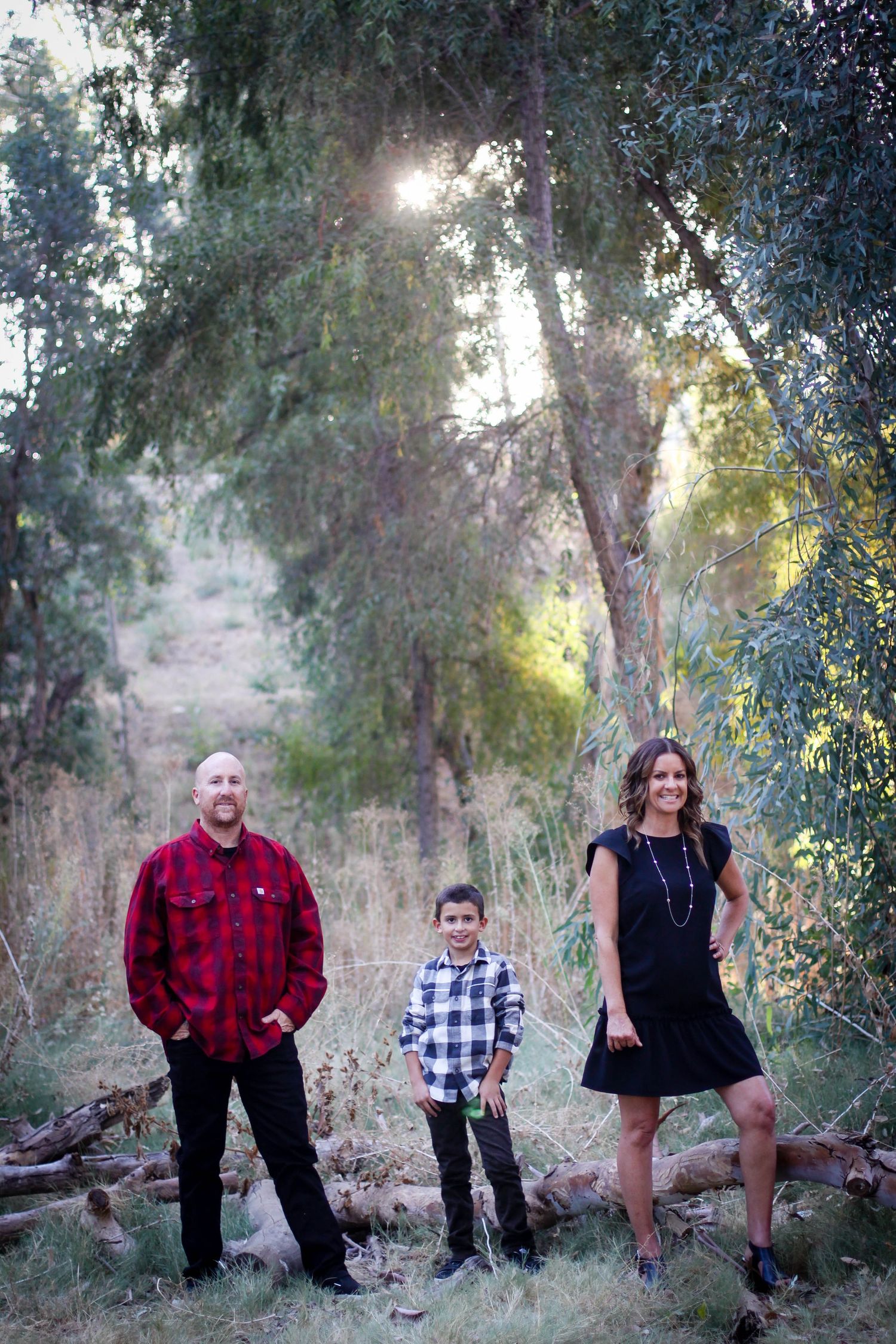 Family members posed casually against trees in outdoor setting wearing mix of plaids and dark colors.
