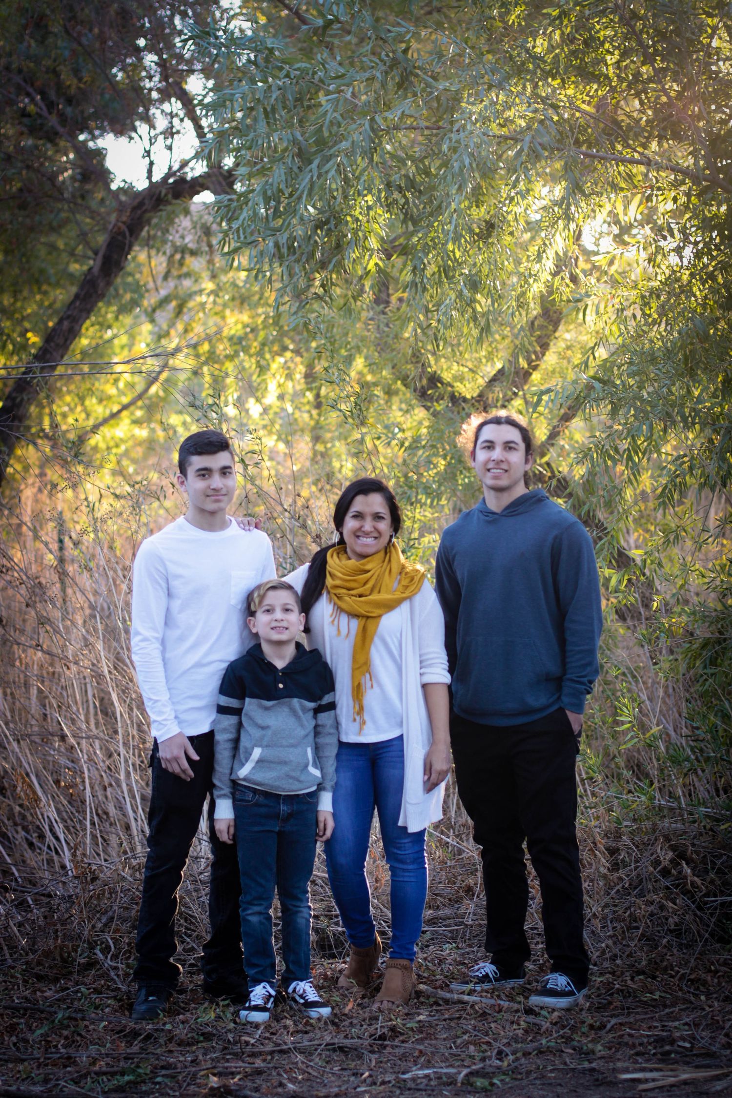 Family group walking together through wooded area during autumn photo session.