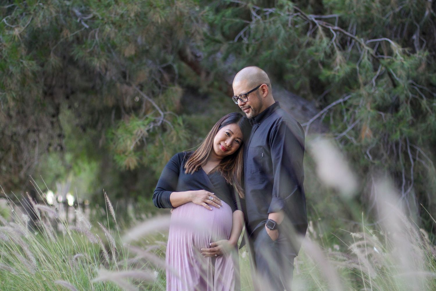 Couple enjoying a romantic moment together outdoors in a natural setting with trees and tall grass.