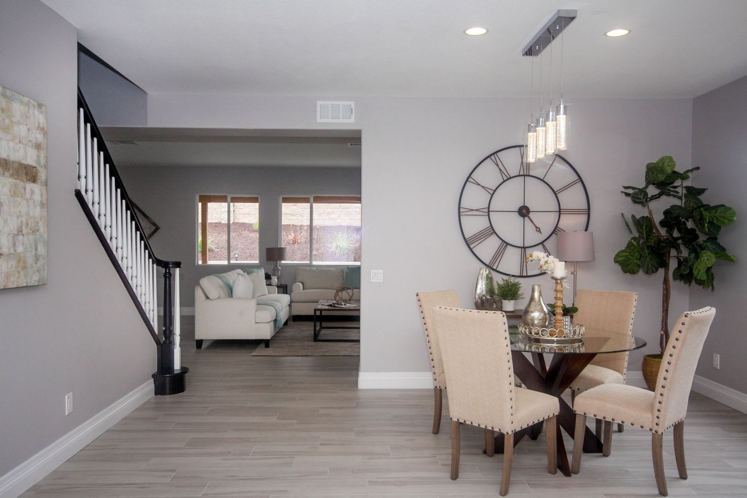 Modern open concept living room with white walls, recessed lighting, and hardwood floors leads to staircase.