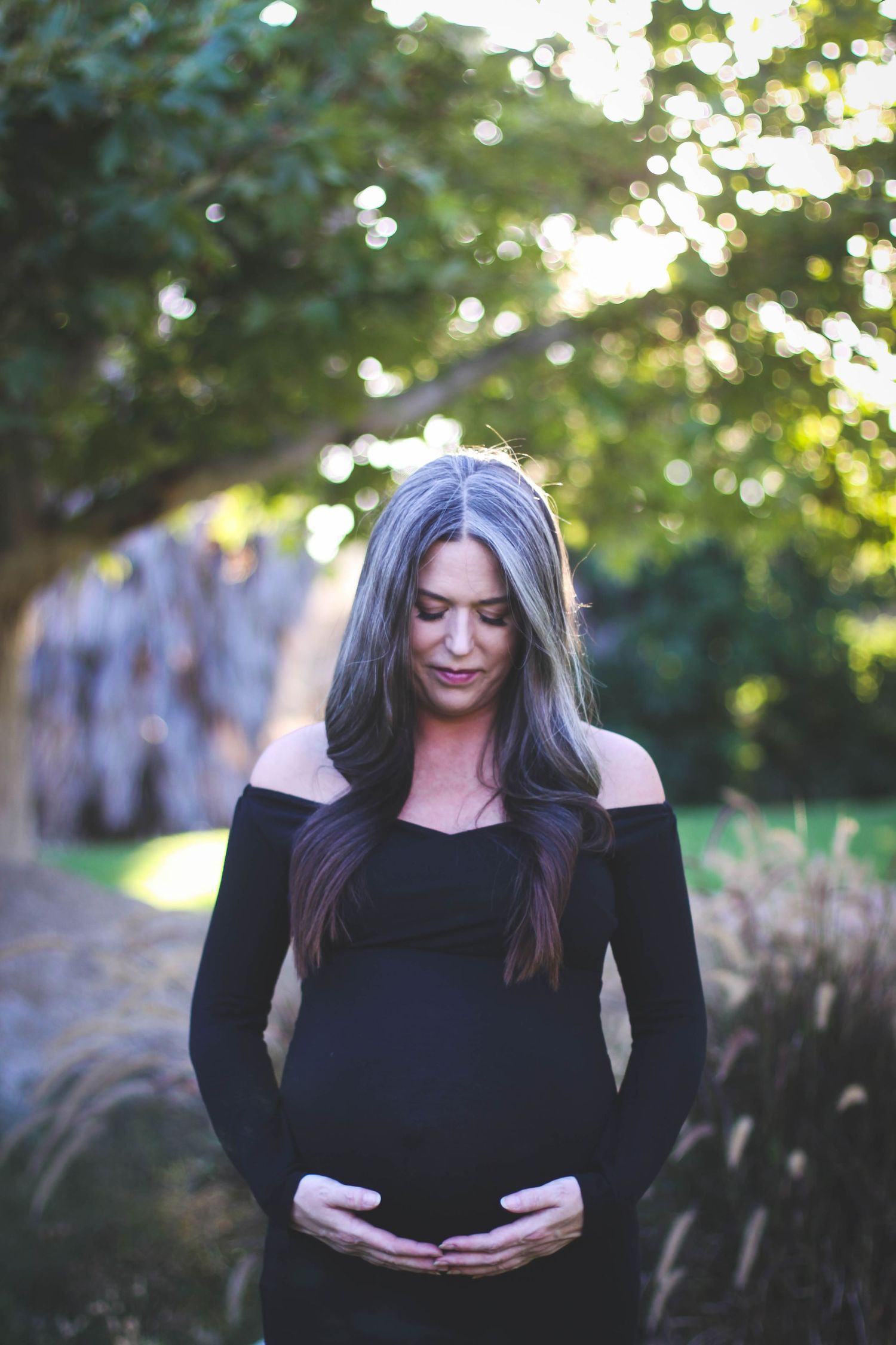 Woman in black top posing outdoors during golden hour with natural lighting.