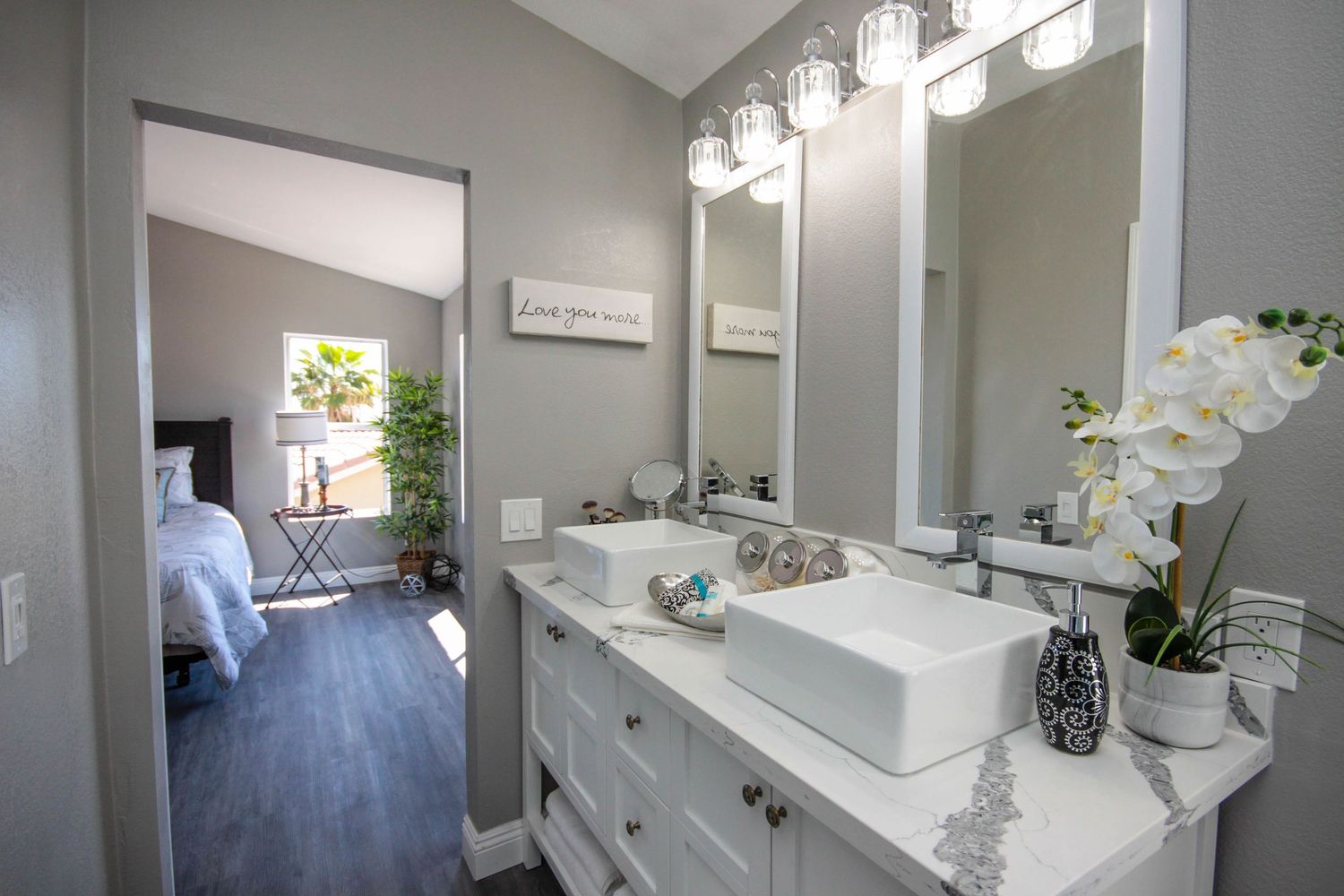 Contemporary bathroom with double vessel sinks, white cabinets and modern lighting fixtures.