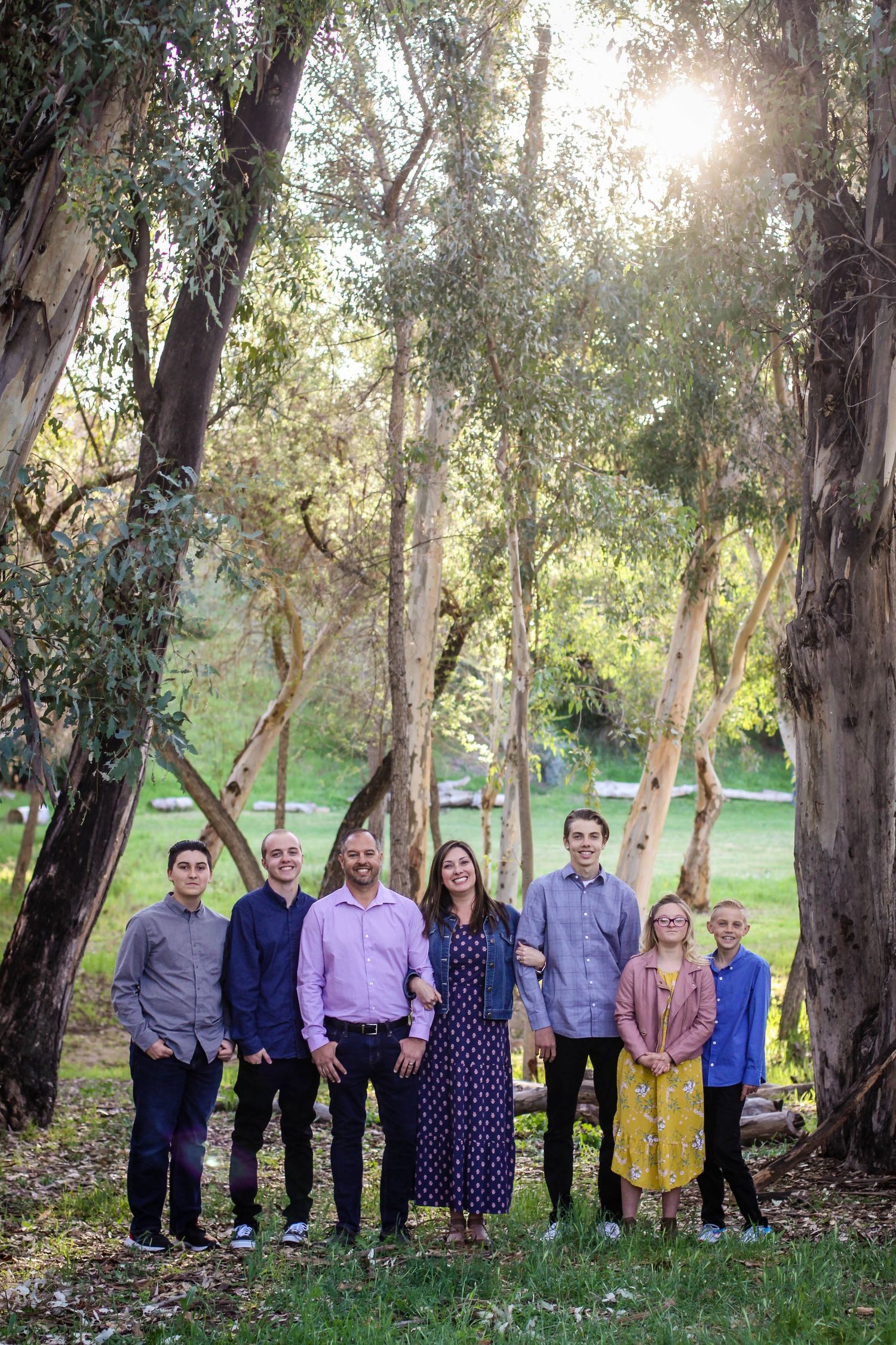 Extended family lined up outdoors against backdrop of eucalyptus trees.