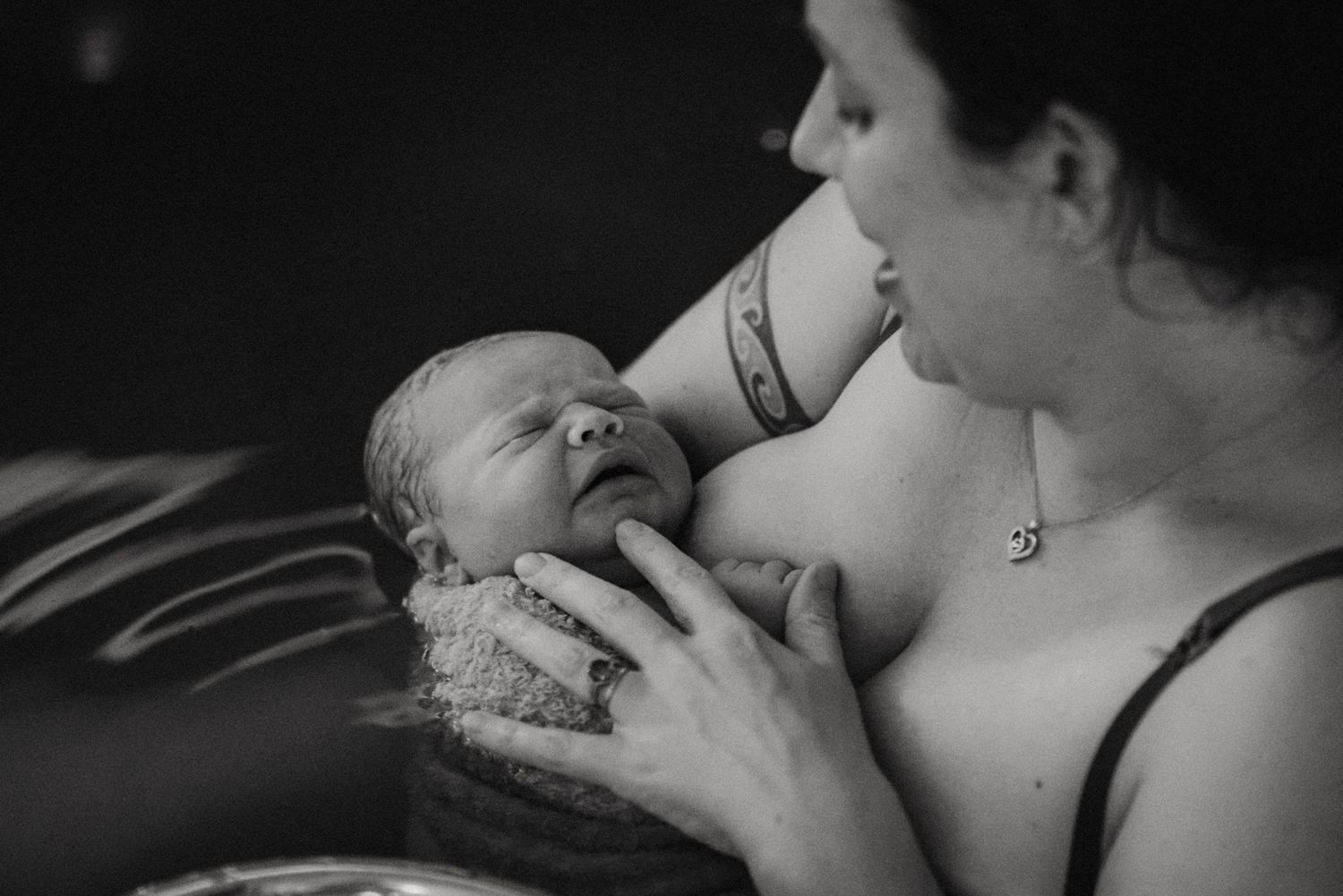 Black and white photo of a mother tenderly holding and breastfeeding her newborn baby.