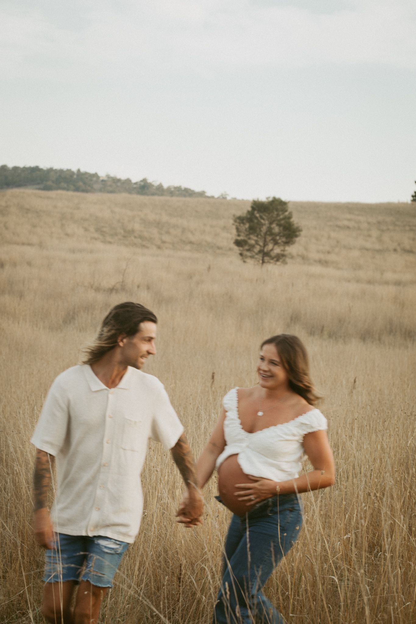 A couple playfully interacts in a golden wheat field on a sunny afternoon.