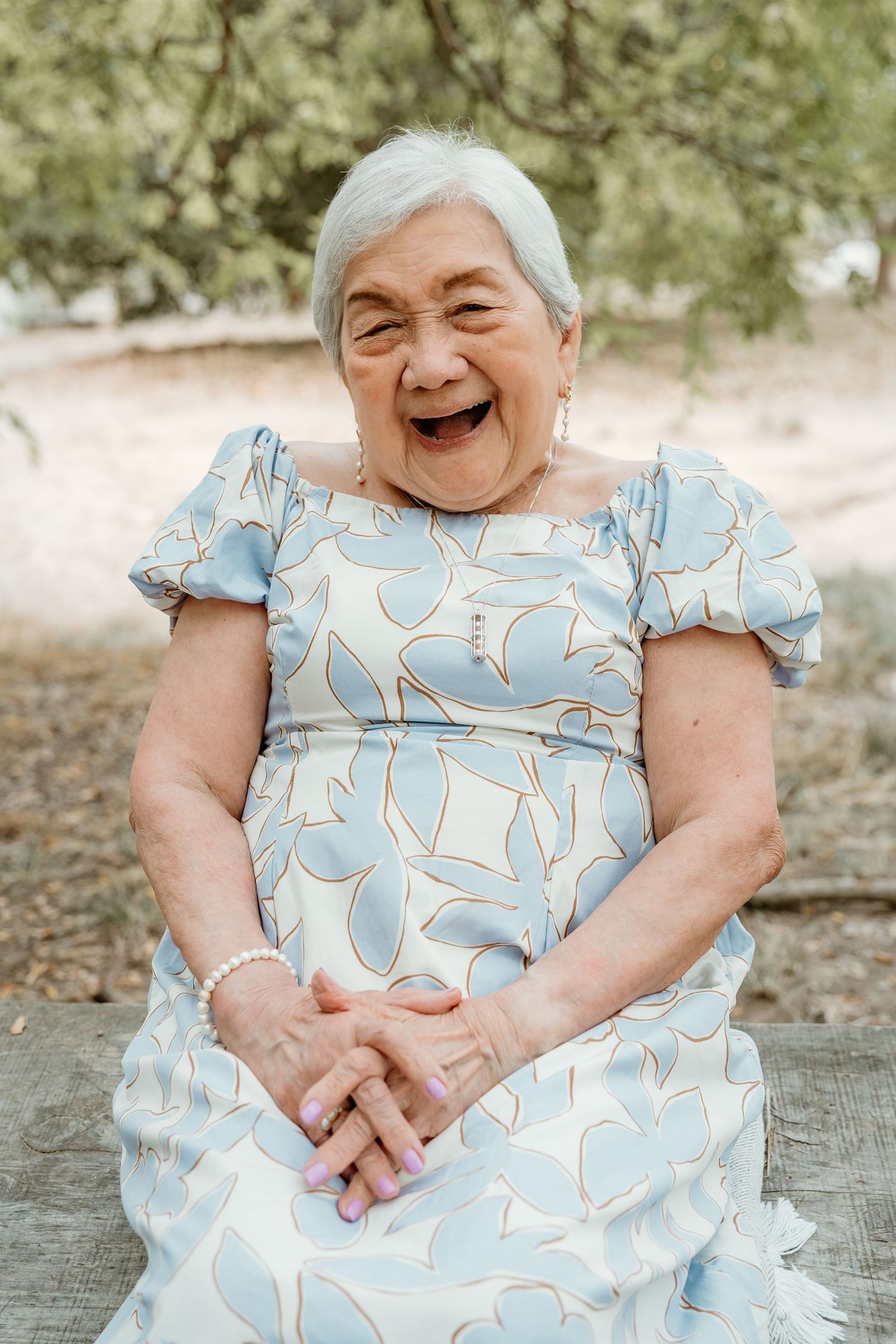 Woman in light blue floral dress sitting outdoors showing genuine joy in a series of candid shots.