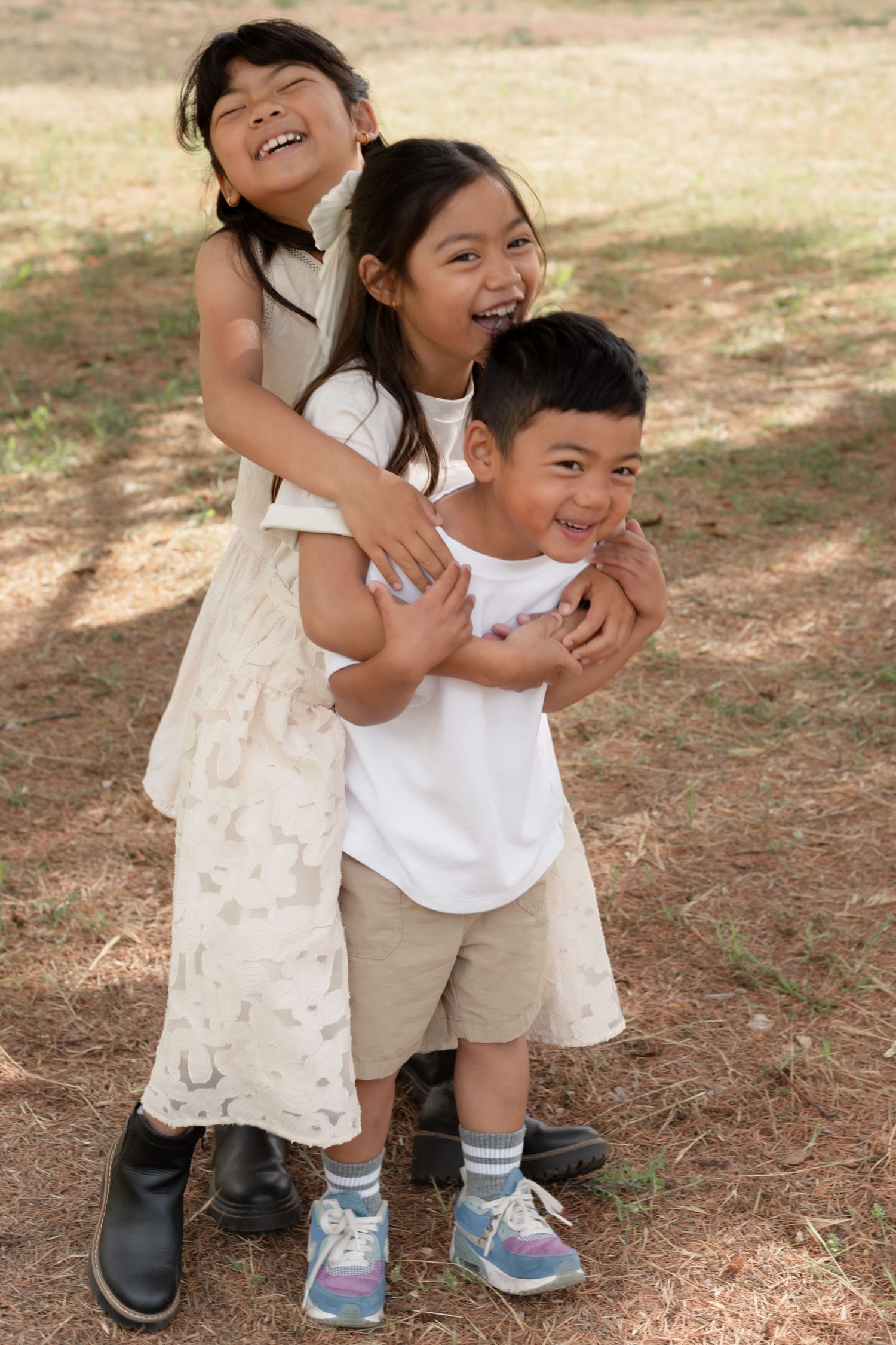 Playful family moment captured on dirt path with children hugging and laughing.