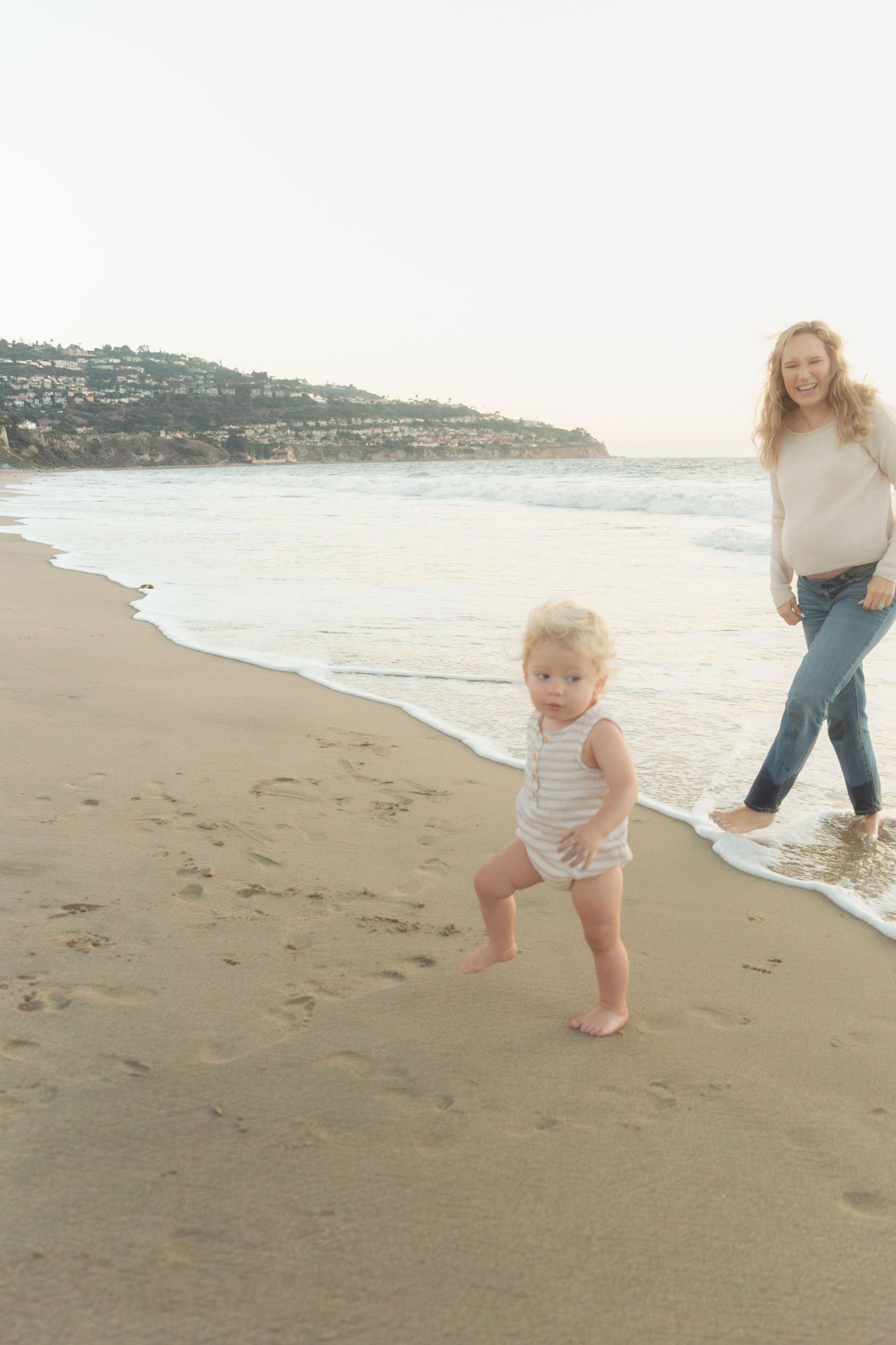 Family playing and running along the shoreline at sunset.
